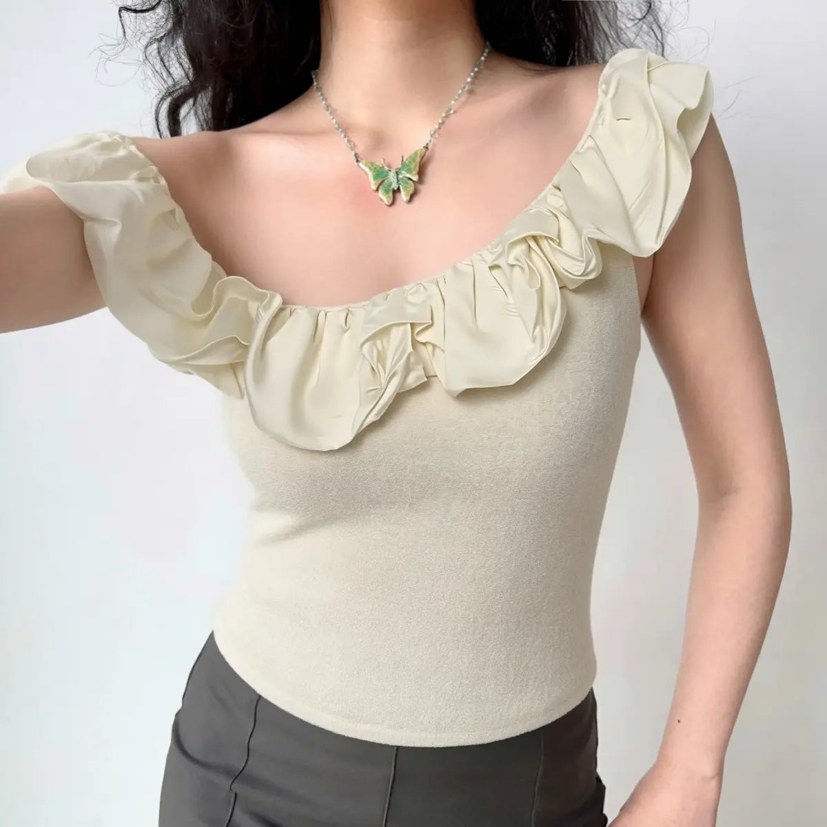 Lifestyle outfit shot off shoulder ruffle cream knit top with casual pants
