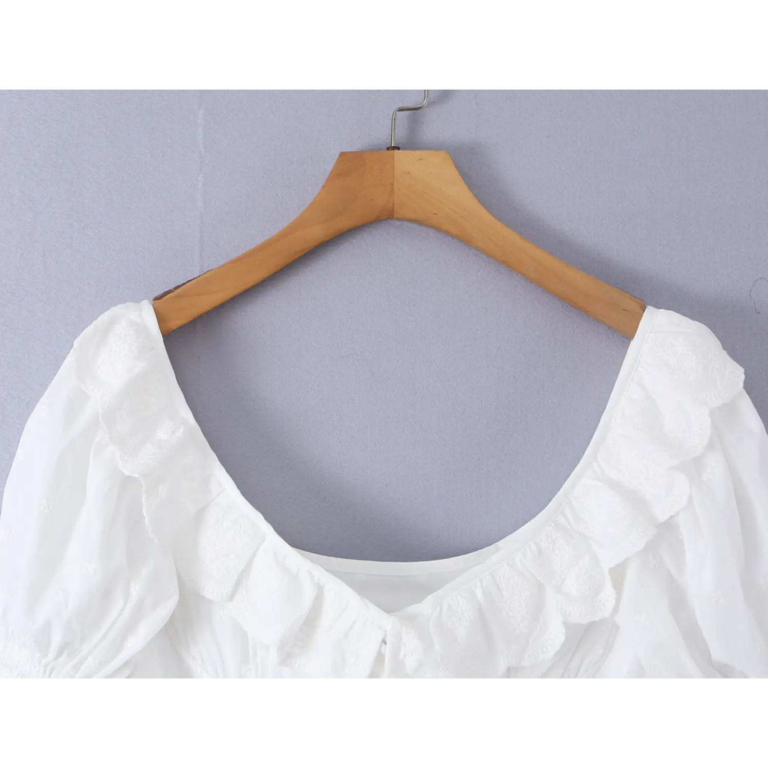 Close up detail shot layered scalloped floral lace ruffle wide square neck of white eyelet corset blouse