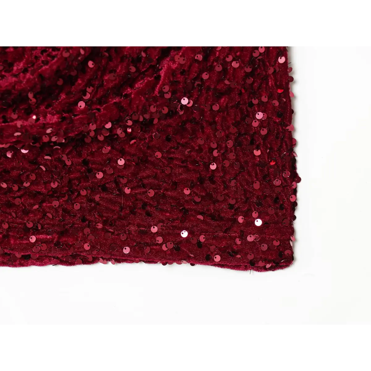 Close-up of the sequined velvet skirt hem on a wine red dress, highlighting the texture, sparkle, and even stitching.