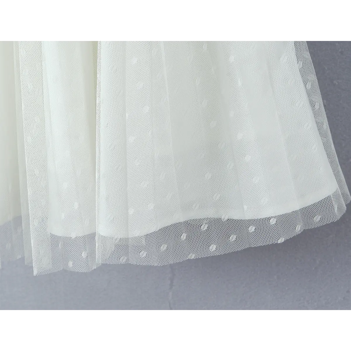 Macro fabric shot of swiss dot mesh tulle, uniform raised dot pattern and lightweight sheer texture for ballet skirt.