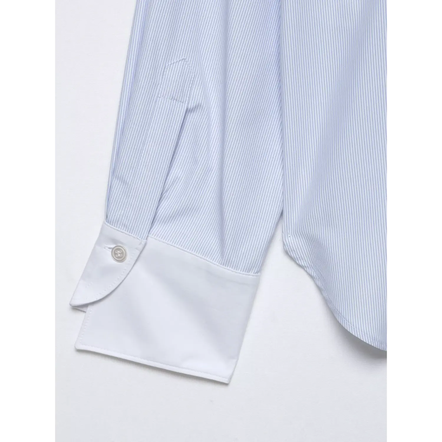 Close-up of contrast white turn-up cuff with matching round white button, fine vertical stripe texture
