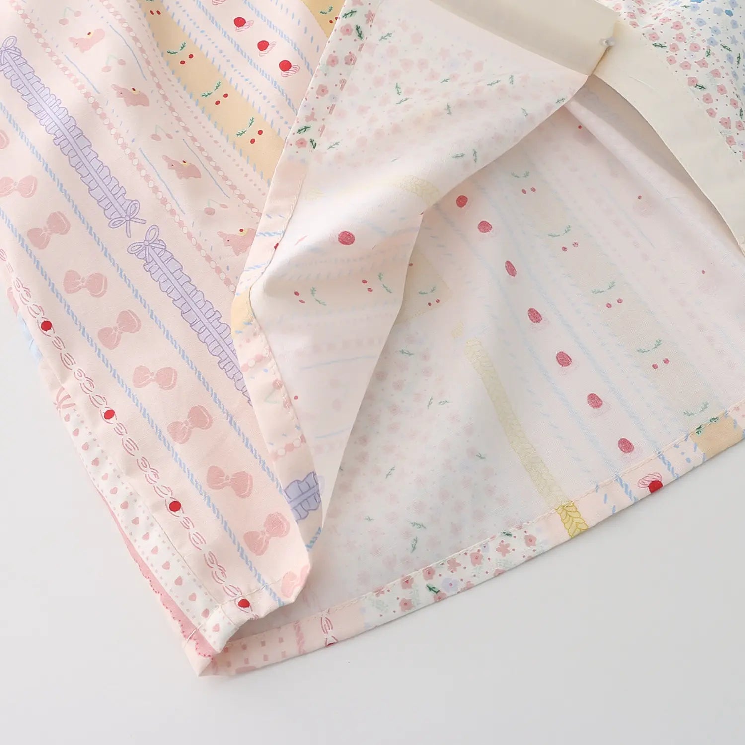 Shirt hem folded double layer lining binding macro close-up, matching print fabric inside & out even double thread hem serging anti-curl lightweight breathable cotton drape texture detail shot