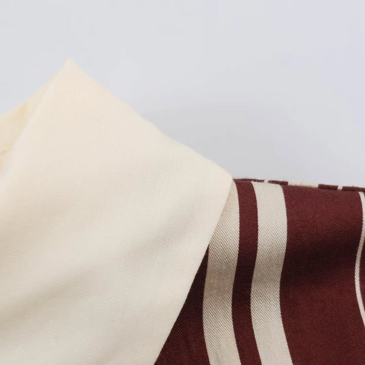 Close‑up of cream contrast cuff on burgundy white stripe three quarter sleeve