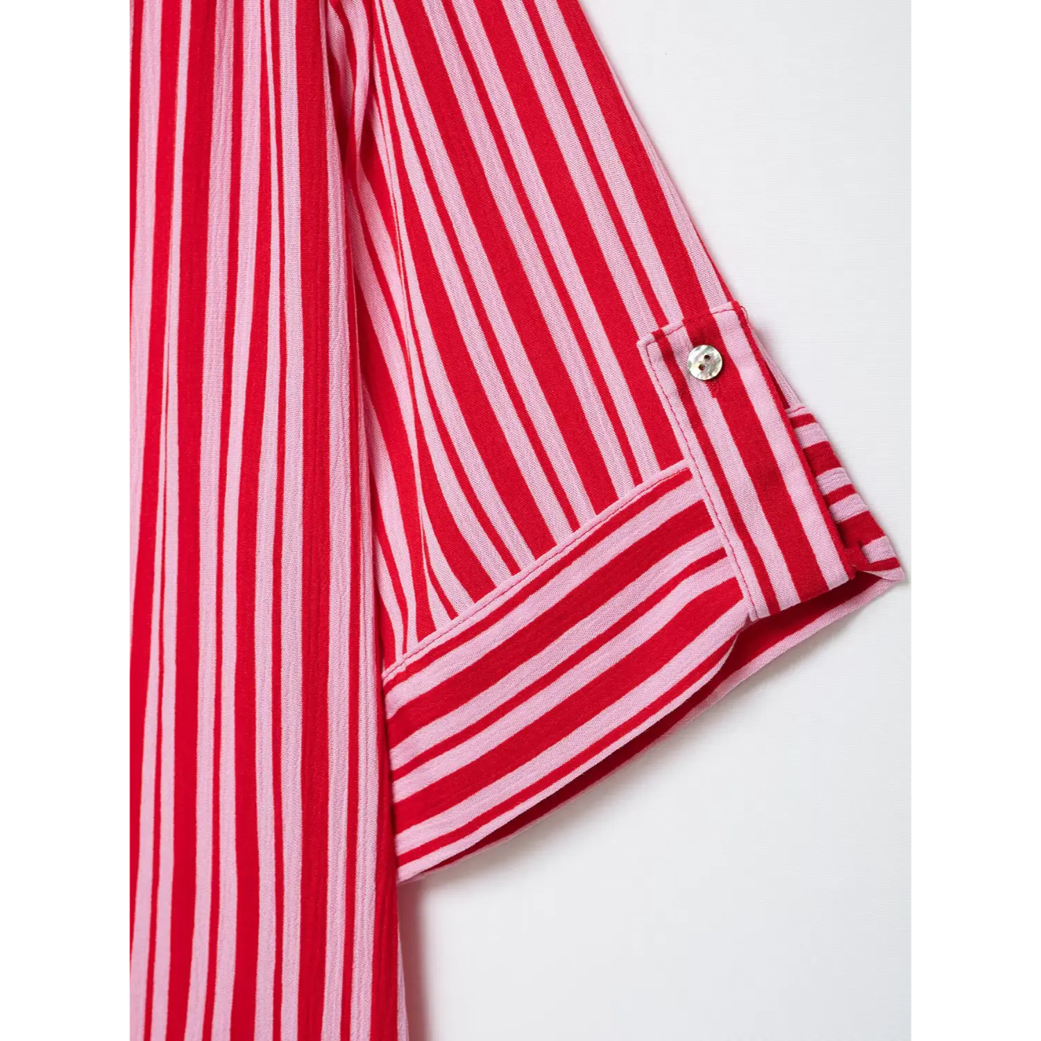 Close-up of tab adjustable rolled sleeve cuff with small round shell button, folded striped cuff construction