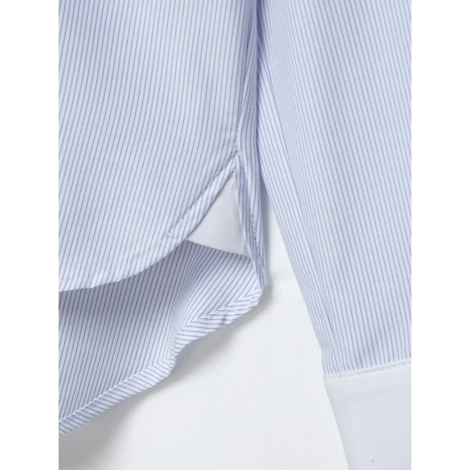 Close-up of side hem split, neat overlock stitching on lightweight blue white pinstripe fabric