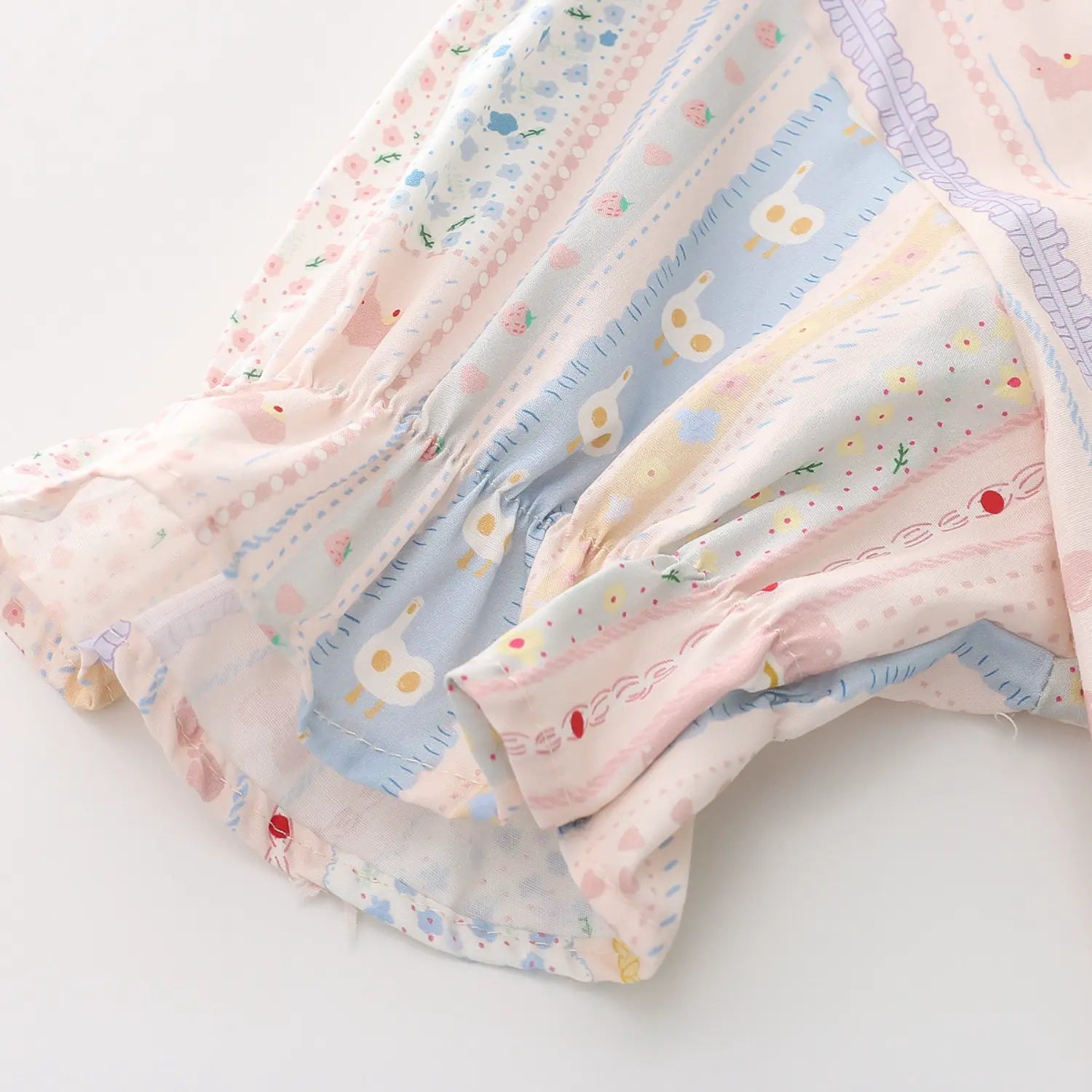 Short puff sleeve elastic ruffle cuff macro close-up, full circle elastic gathering form fluffy frill hem double thread binding wash-resistant clear cartoon print fabric texture detail shot