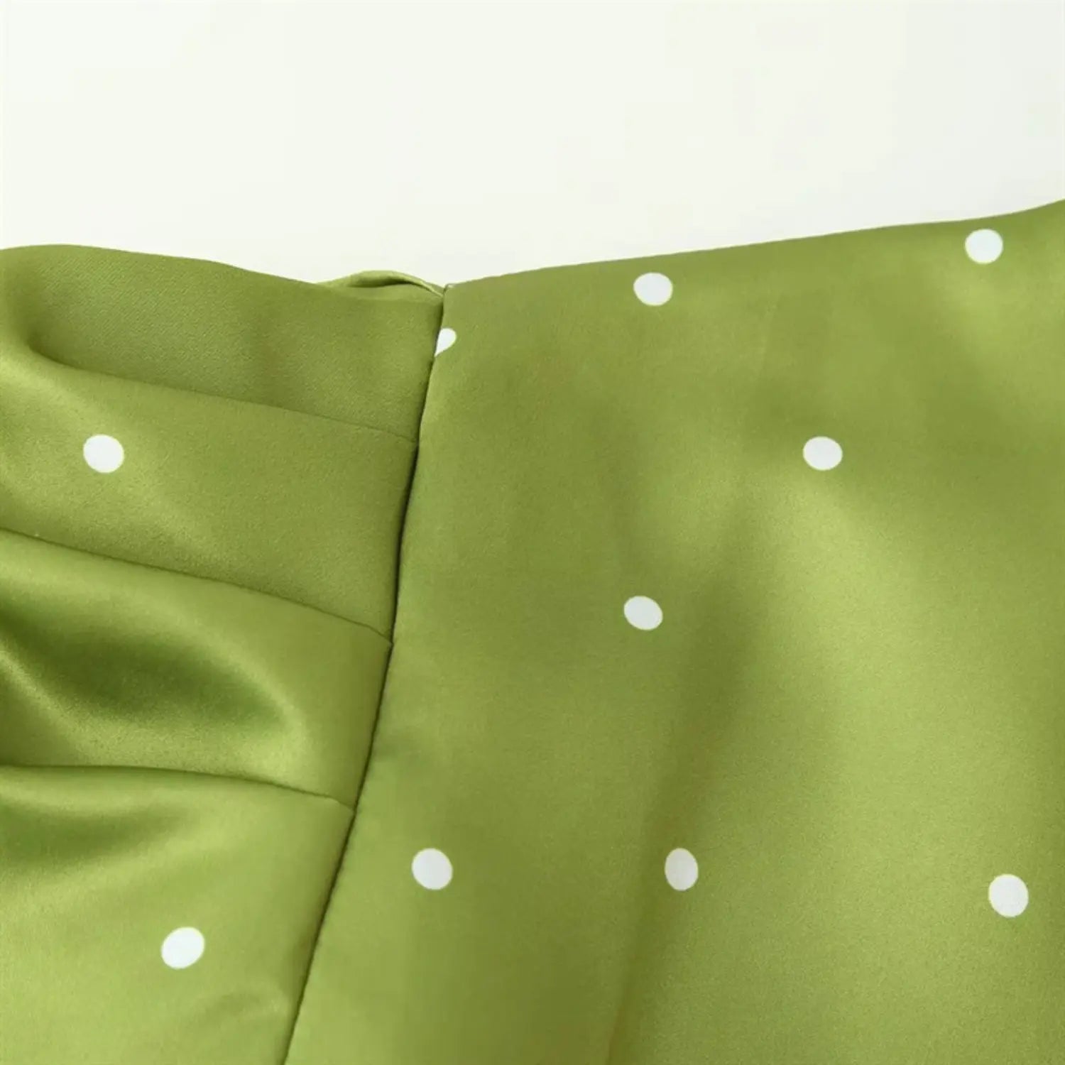 Side partial shot of bubble sleeve, natural fabric draping creases, consistent white polka dot printing, lightweight glossy satin