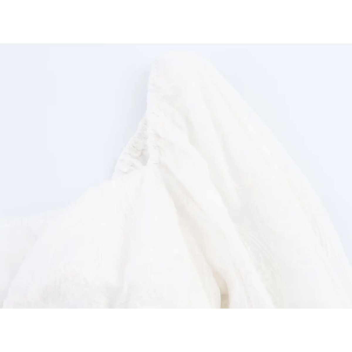 Close-up of shoulder elastic ruffle detail on white puff sleeve embroidered crop top