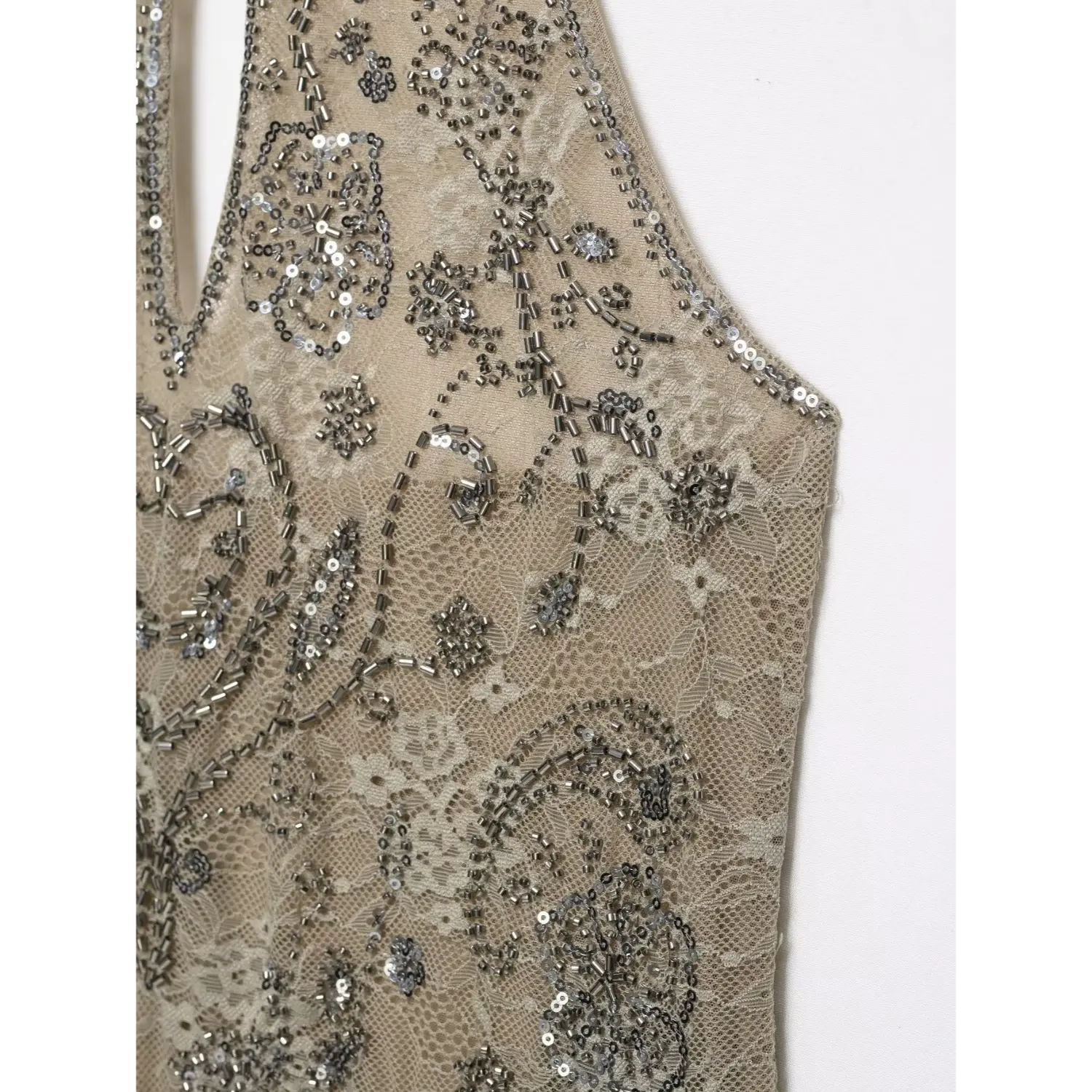 Side armhole close‑up showing ornate silver beading sequin floral pattern on semi‑sheer beige lace halter top