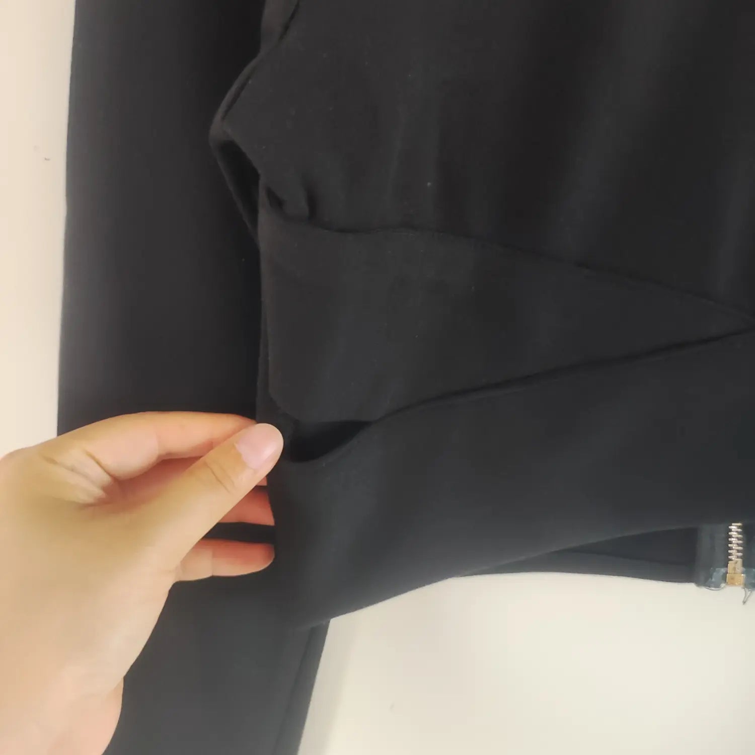 Hand showing side waist cutout detail of black wrap cropped long sleeve top