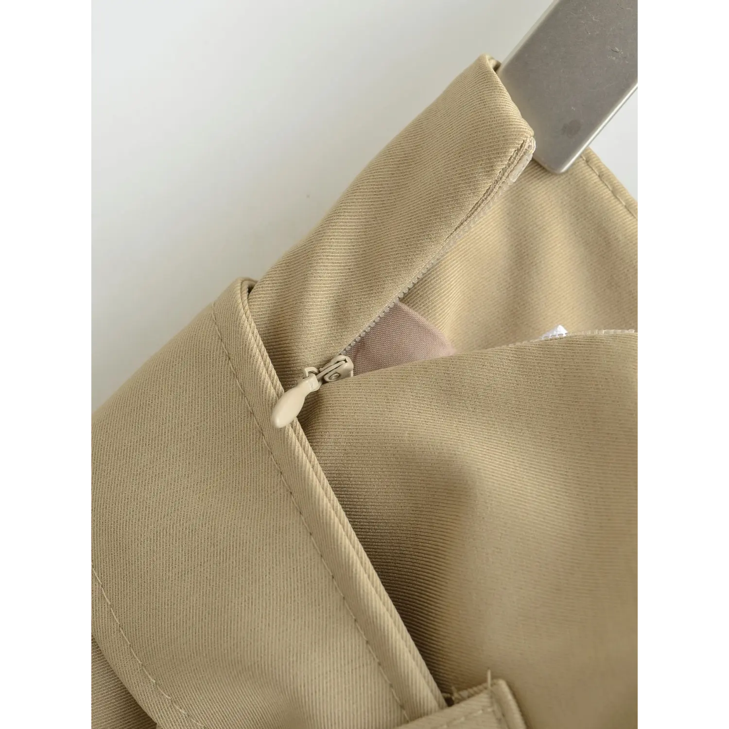 Side invisible zipper inner lining flat close-up, smooth hidden zipper matching color binding zipper head neat lining splice overlock white background shot