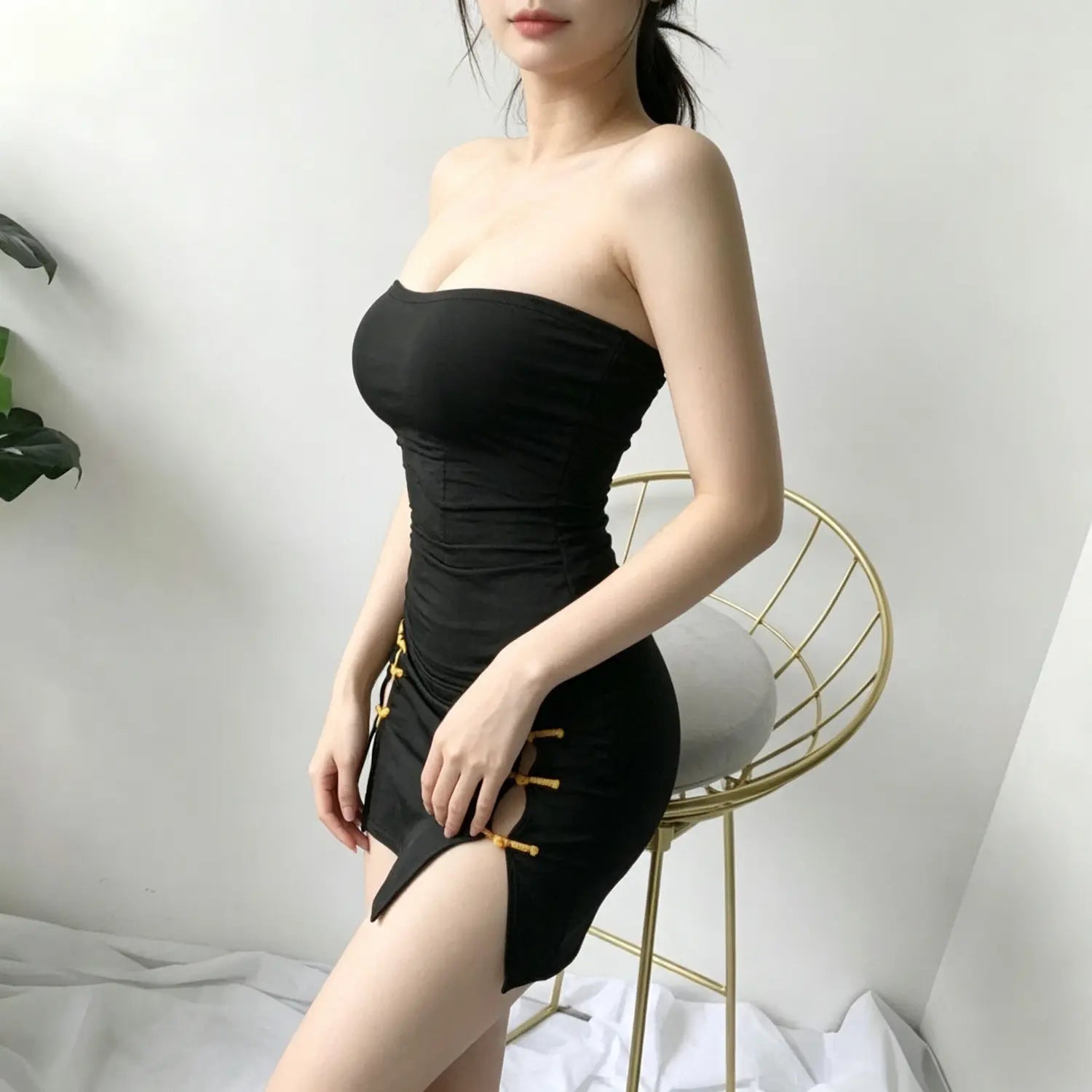 Side profile shot model in black strapless bodycon mini dress with chinese knot decor | Detail