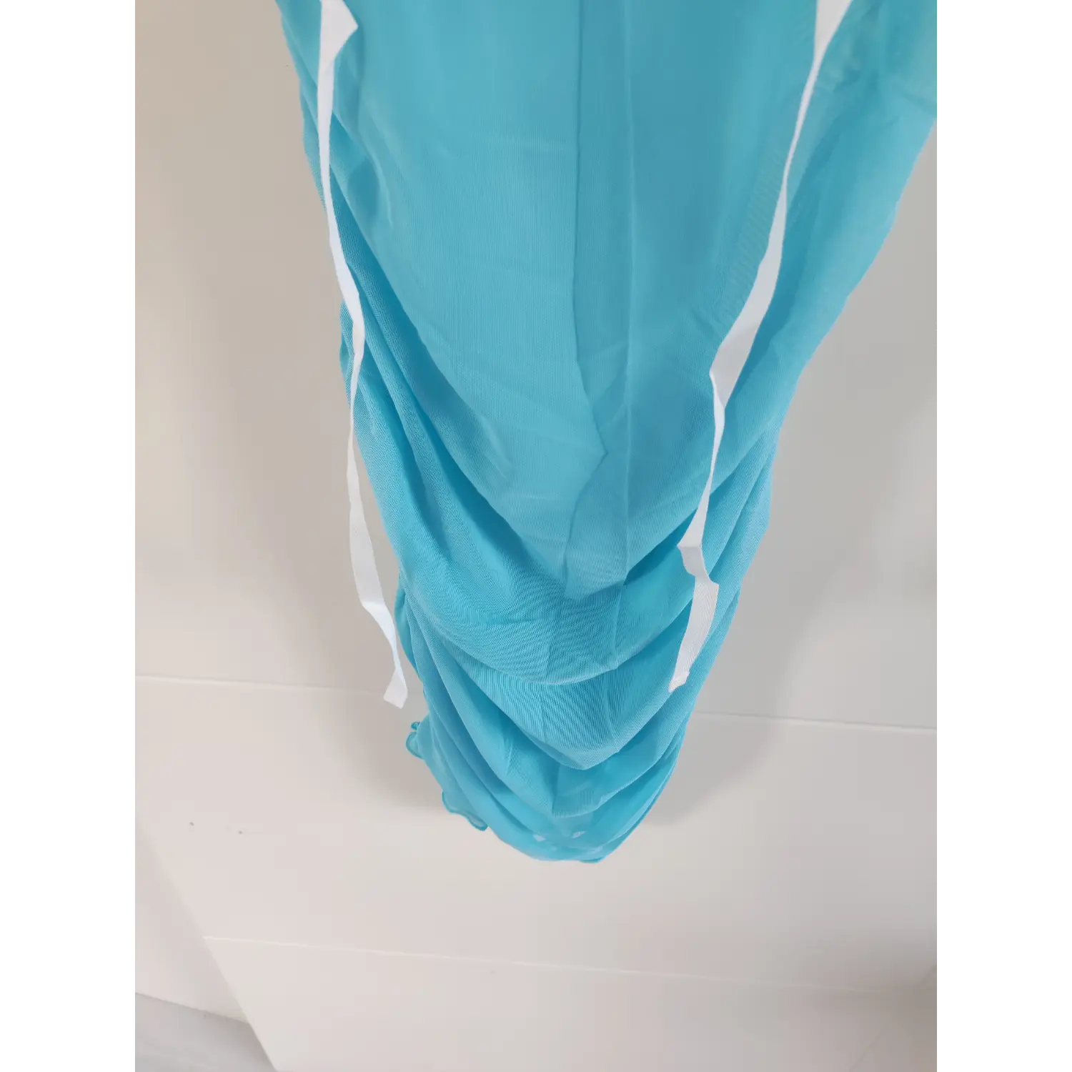 Macro shot of side ruched hem on light blue sheer mesh dress, gathered mesh fabric bodycon skirt detail