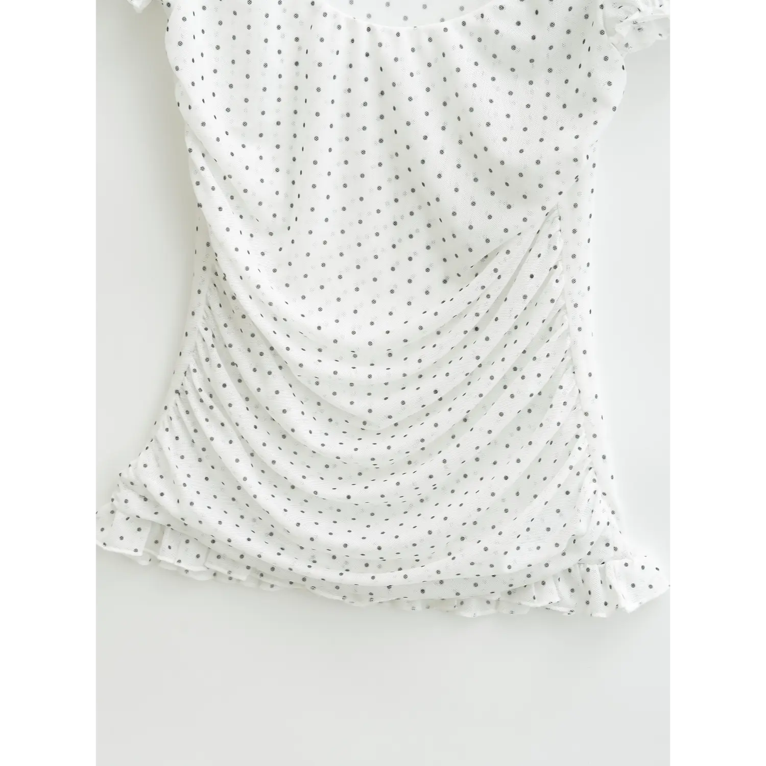 Detail shot of side ruched gathering and frilled bottom hem on sheer polka dot mesh casual top