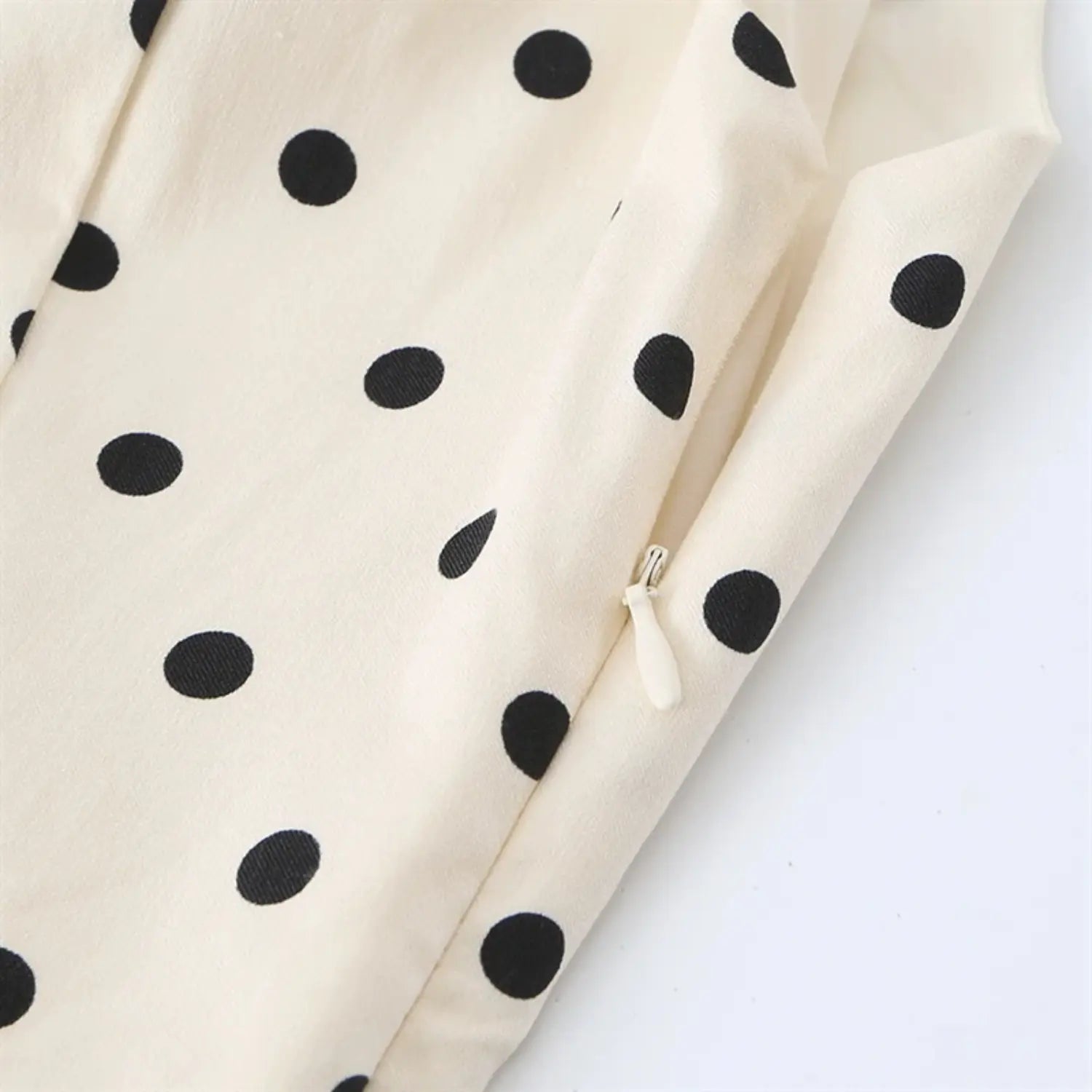 Side hidden zipper close-up, matching off-white plastic pull tab, neat serging seam along zipper placket