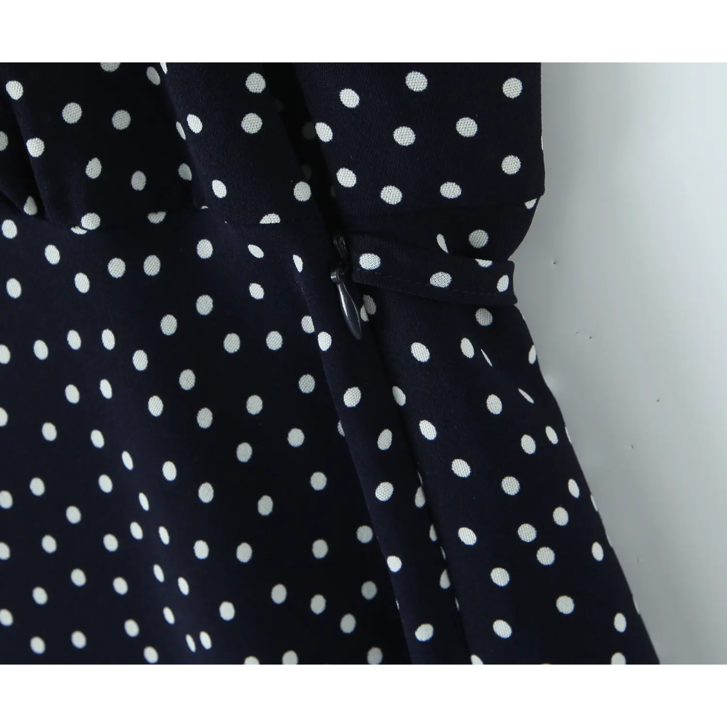 Side teardrop pull invisible zipper polka dot dress macro close-up, matching dot fabric hidden zipper smooth slide waist hip concealed zip construction detail shot