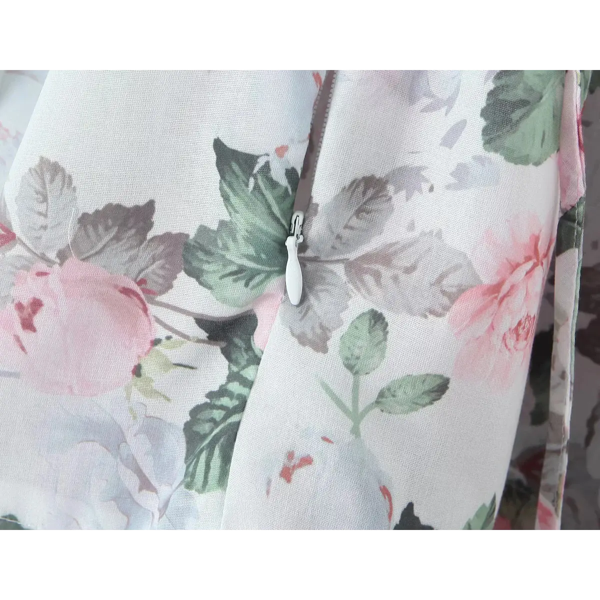 Close-up of the white side zipper on a pink rose print dress.