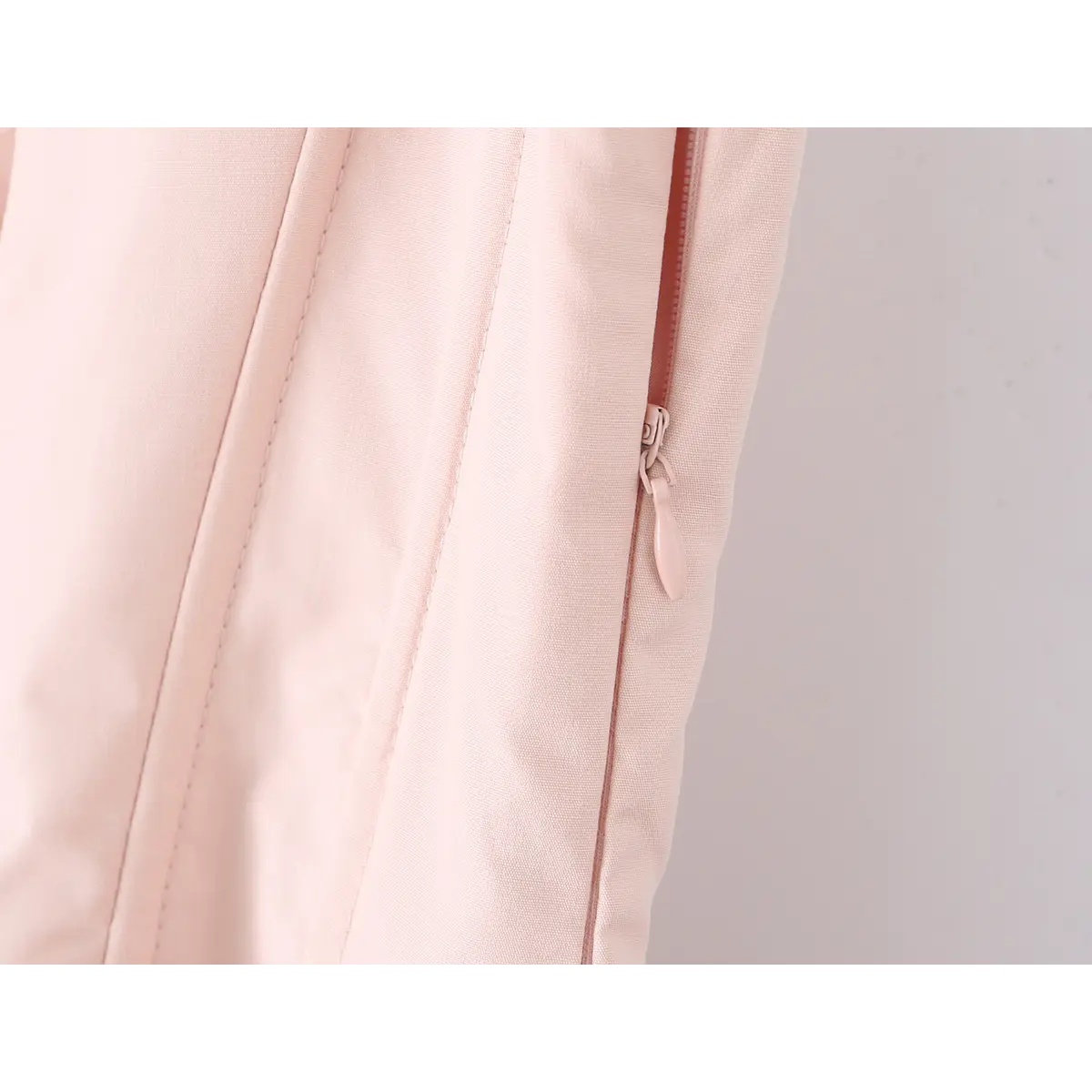 Close-up of the side zipper on a light pink corset-style dress.
