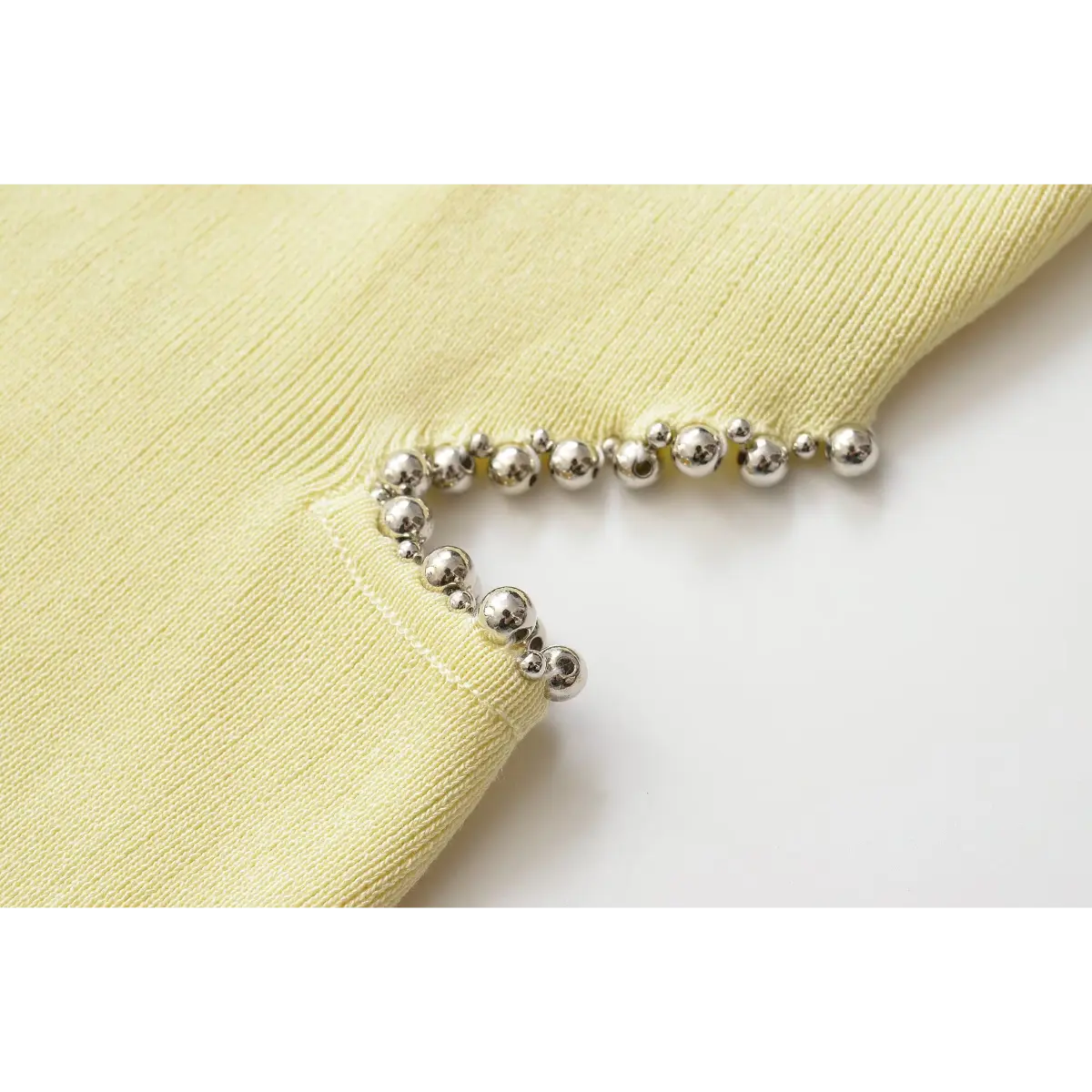 Close of polished silver ball beads surrounding garment cutout