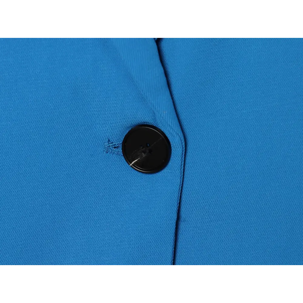 Close-up of black button on blue twill fabric