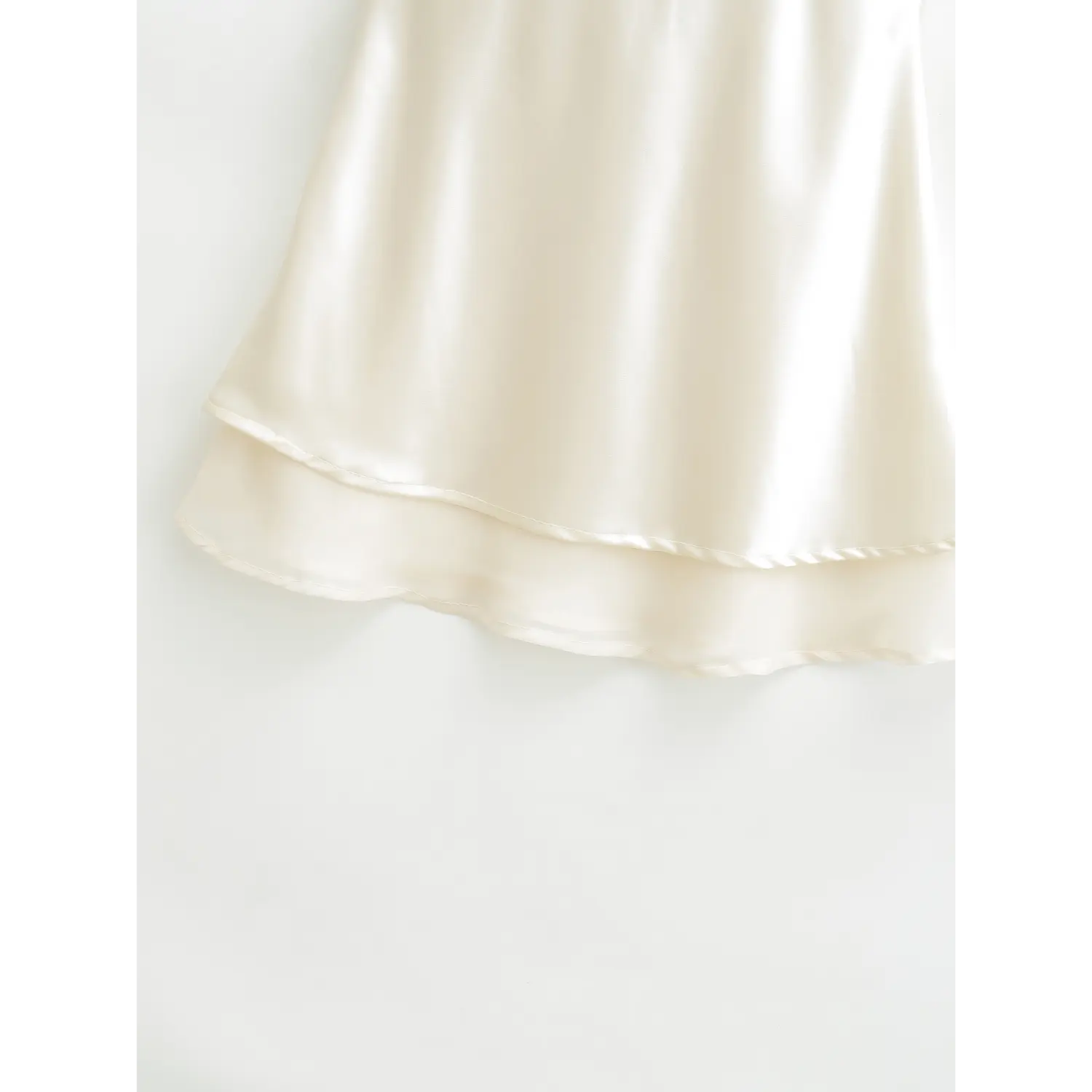 Skirt double layered hem macro close-up, top satin + sheer mesh underlayer joint wavy binding stitching staggered drape fabric detail shot
