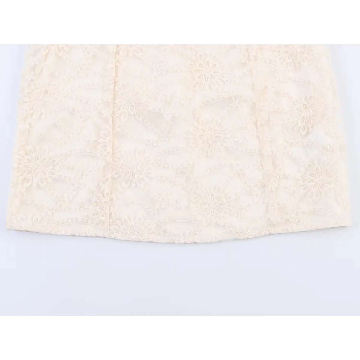 Close-up of finished skirt hem and vertical seam detail on beige floral embroidered mini dress