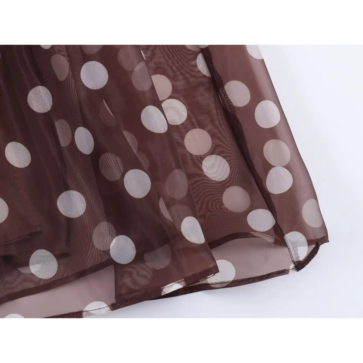 Close-up of finished skirt hem, lightweight sheer brown fabric and white polka dot pattern