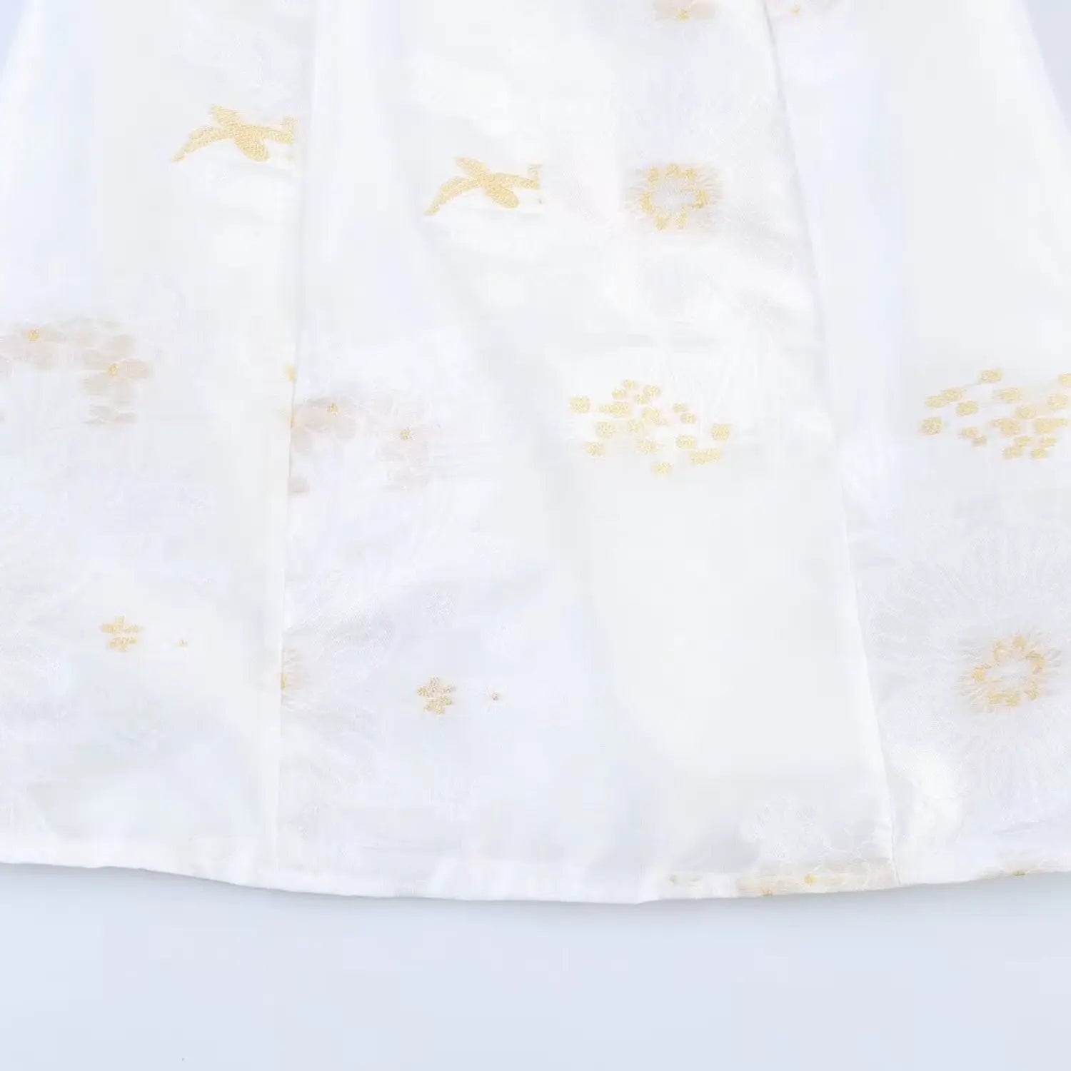 Lower skirt fabric close-up, vertical waist darts shaping, scattered golden bird & daisy embroidery, matte white jacquard texture