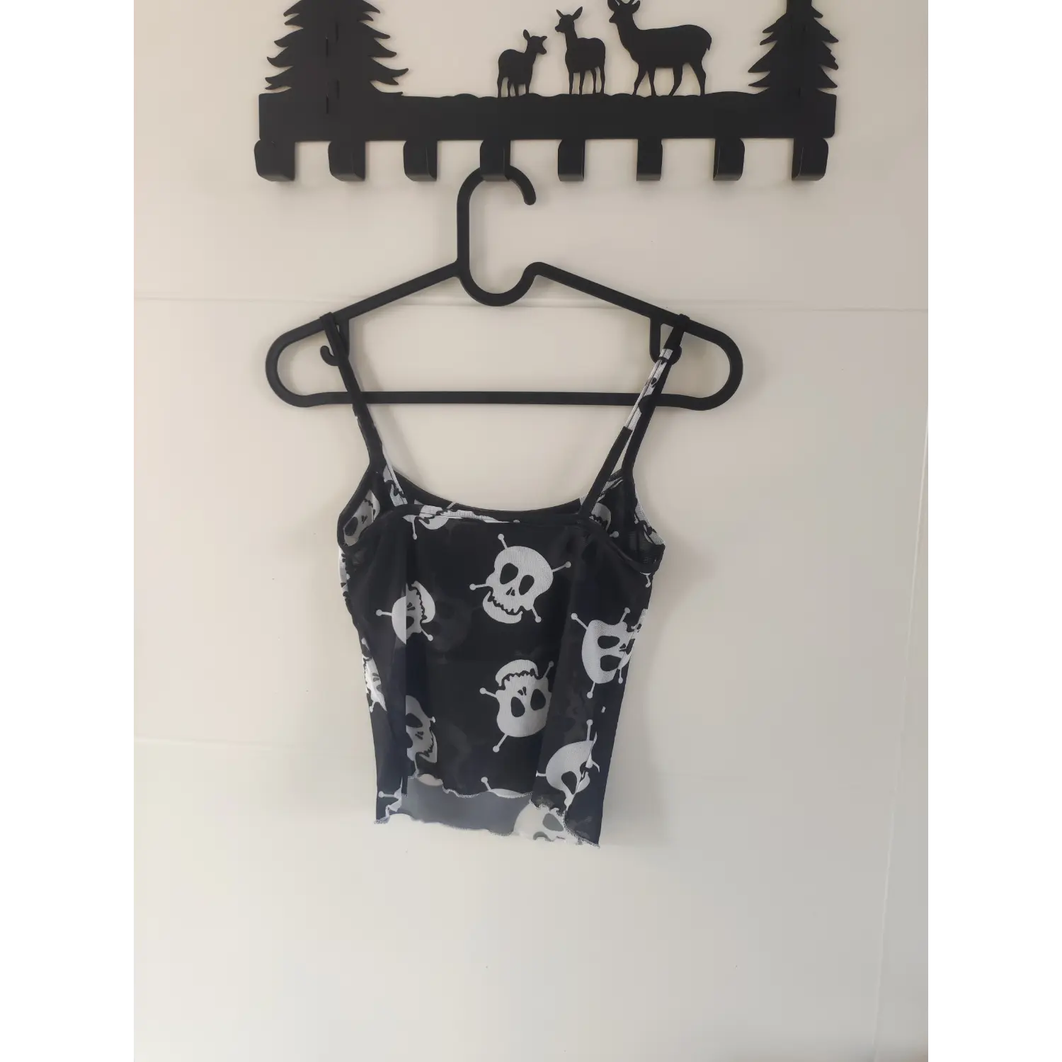 Back hanging shot of black sheer mesh skull print crop cami, thin adjustable straps, lettuce hem gothic tank top