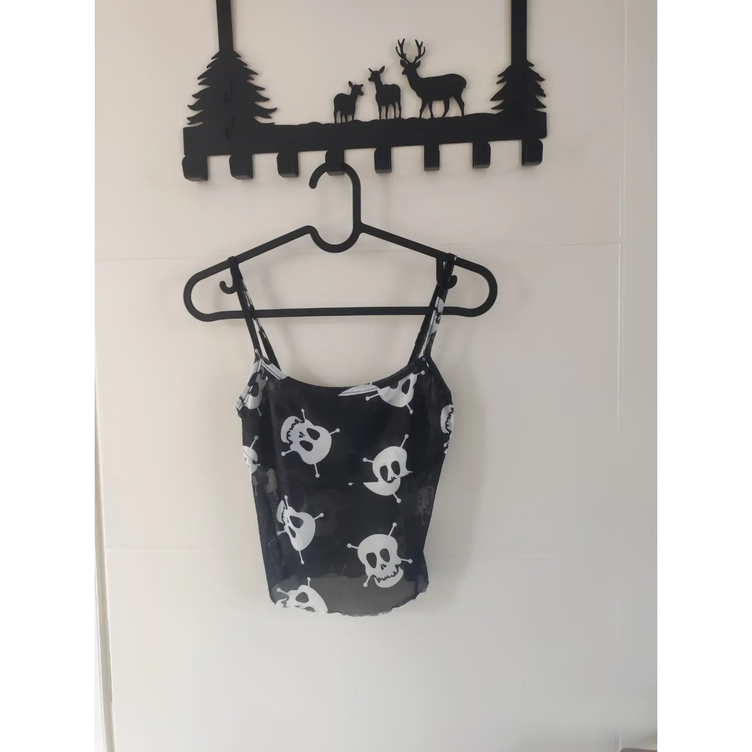 Front hanging view black skull print sheer mesh camisole on black hanger, crop spaghetti strap goth tank top