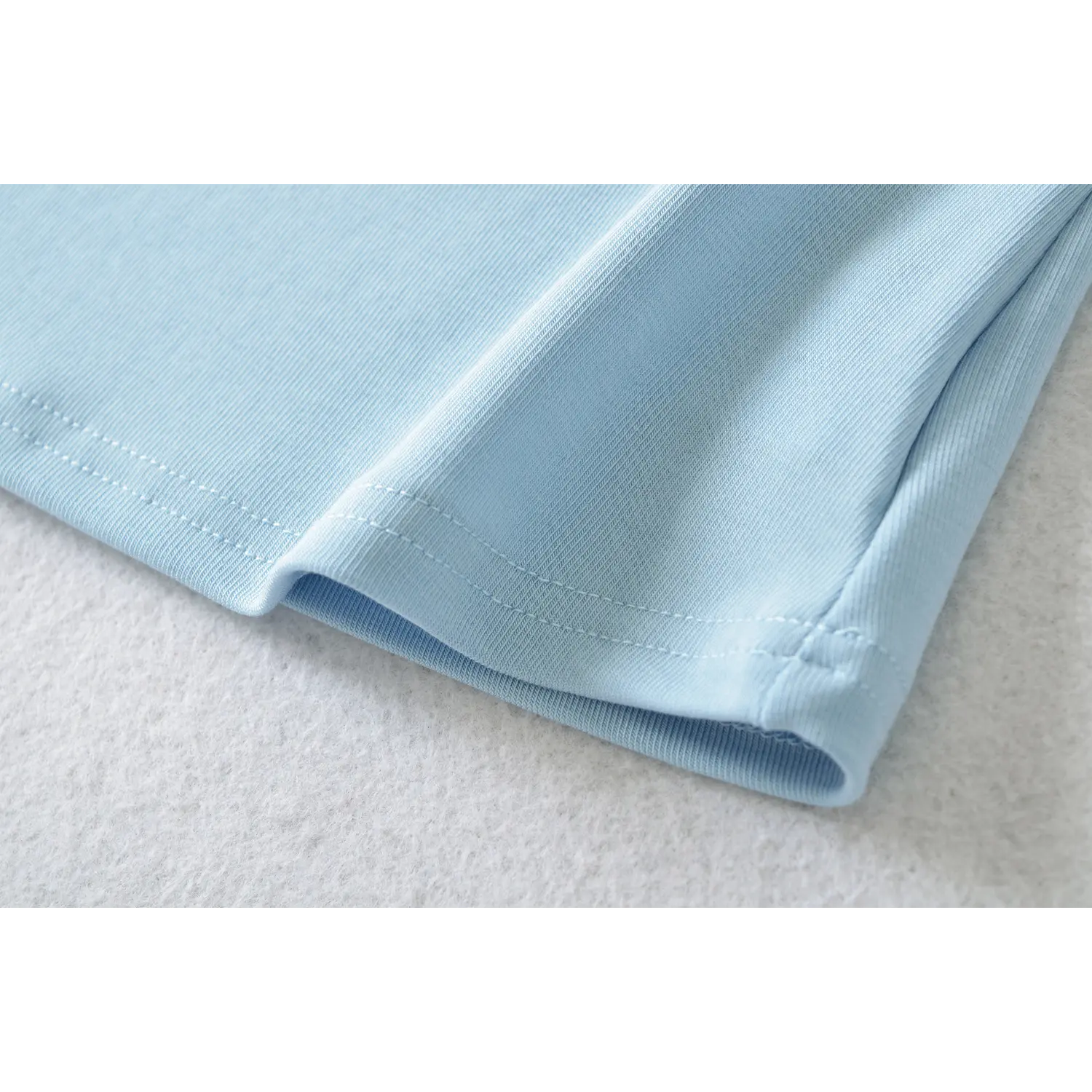 Close up light blue camisole bottom hem, uniform double row stitching, smooth vertical rib fabric curved hem design