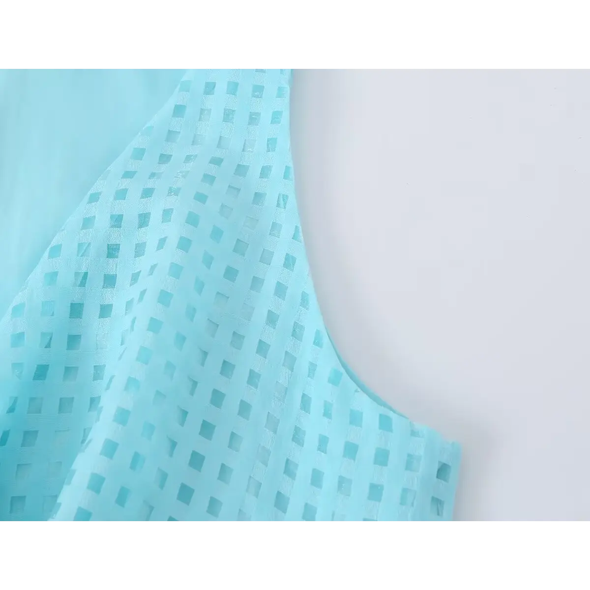 Close of semi-sheer square jacquard fabric on cyan sleeveless mini dress