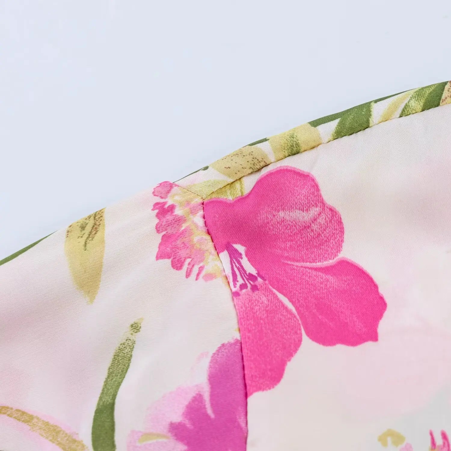 Sleeve cap armhole close-up, neat finished stitching, continuous floral print layout