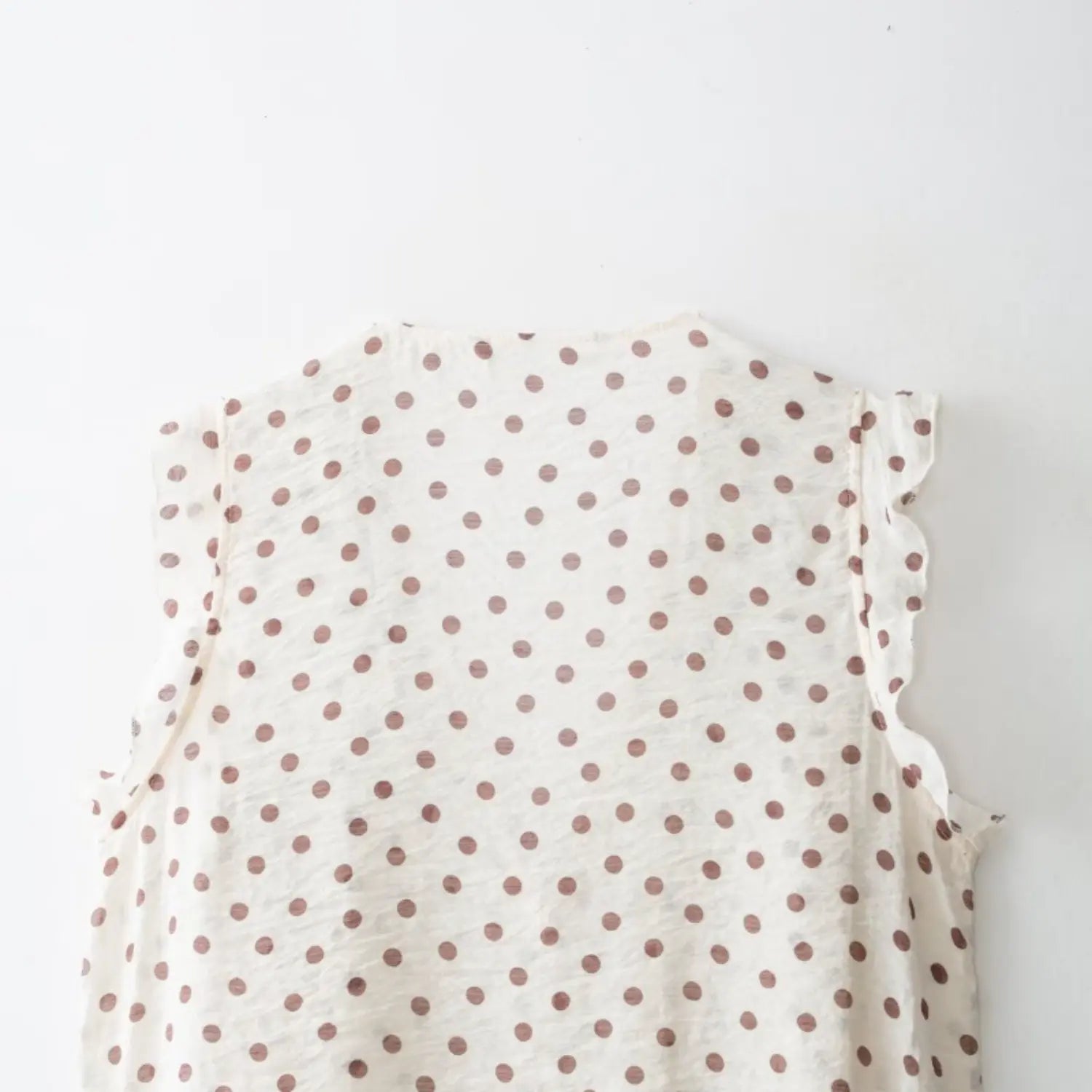 Full back flat partial shot, simple plain back panel, matching ruffle edge on arm openings
