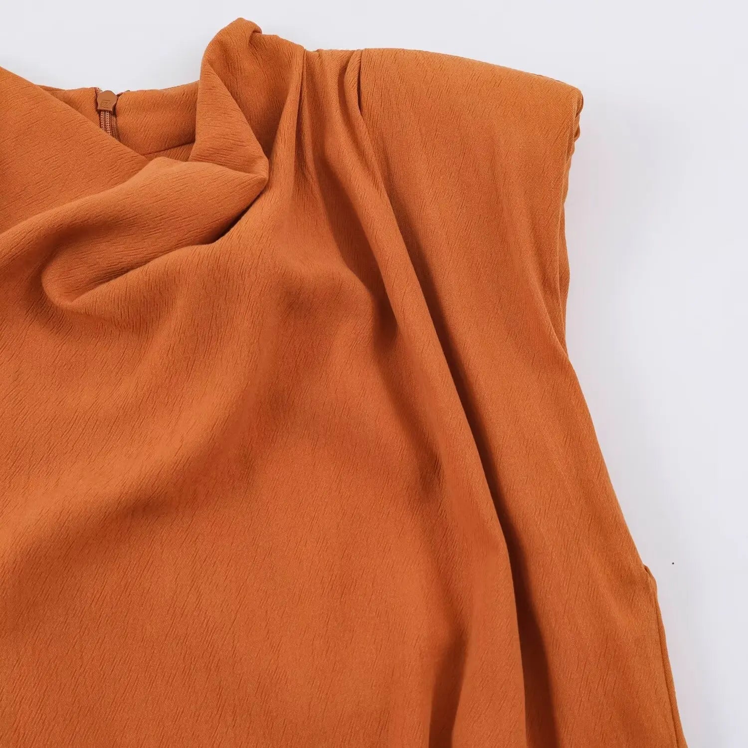 Partial shot of shoulder draped fabric, subtle vertical textured woven material in rust orange