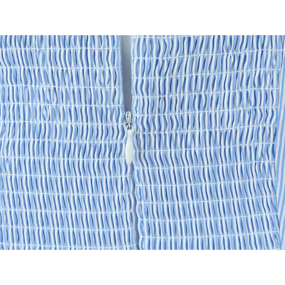 Close-up of the smocked back panel and hidden zipper on a blue and white striped halter dress, showing the stretchy texture and zipper pull.