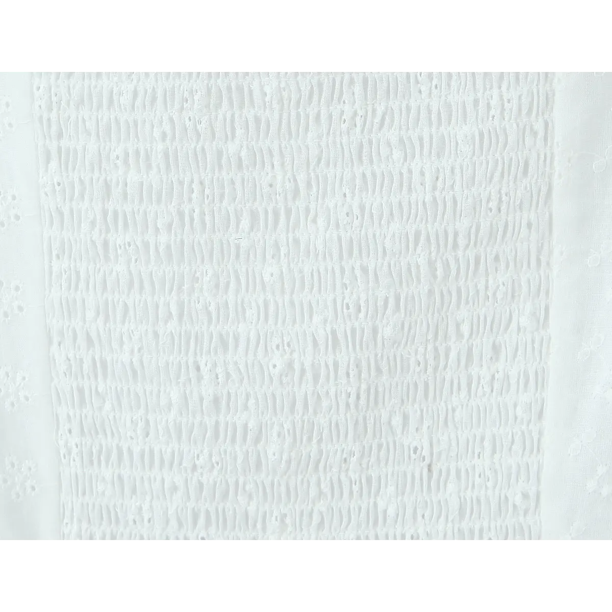 Close-up of the smocked back panel on a white eyelet embroidered bustier top, highlighting the gathered texture and eyelet pattern.
