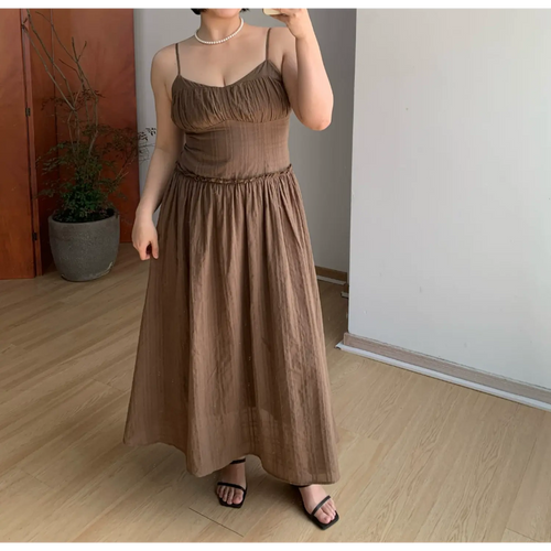 Casual front indoor mirror full shot of mocha brown textured cami maxi dress, ruched sweetheart bust, ruffled empire waist, voluminous gathered flowy long skirt, thin adjustable spaghetti straps, lightweight soft matte fabric, black thin strap slide sandals, minimalist neutral room decor