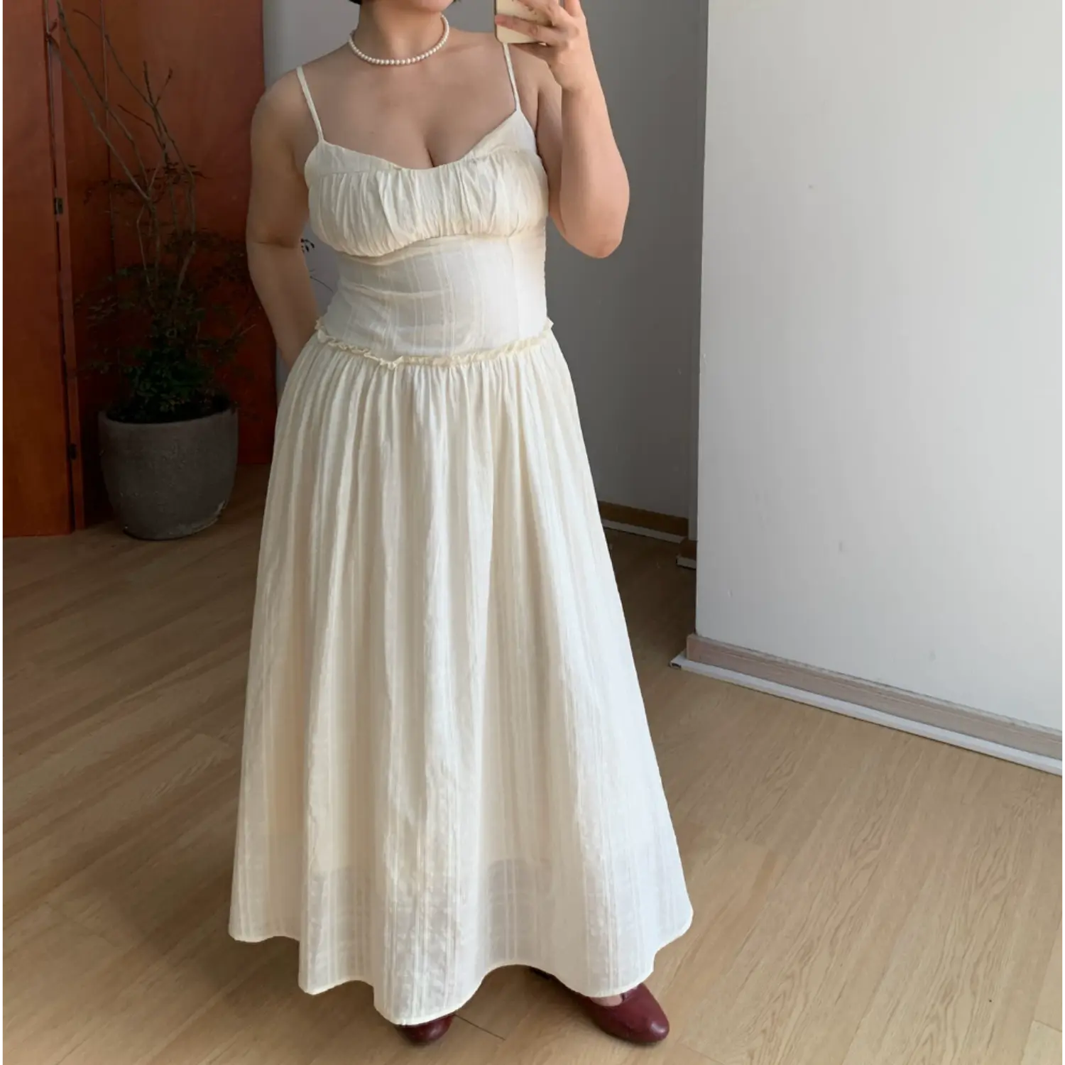 Plain front indoor mirror full shot of lightweight textured cami maxi dress, vertical waffle knit fabric, ruched sweetheart V bust, delicate ruffle empire waist seam, ultra flowy floor-length skirt, adjustable thin spaghetti straps, neutral minimalist home interior