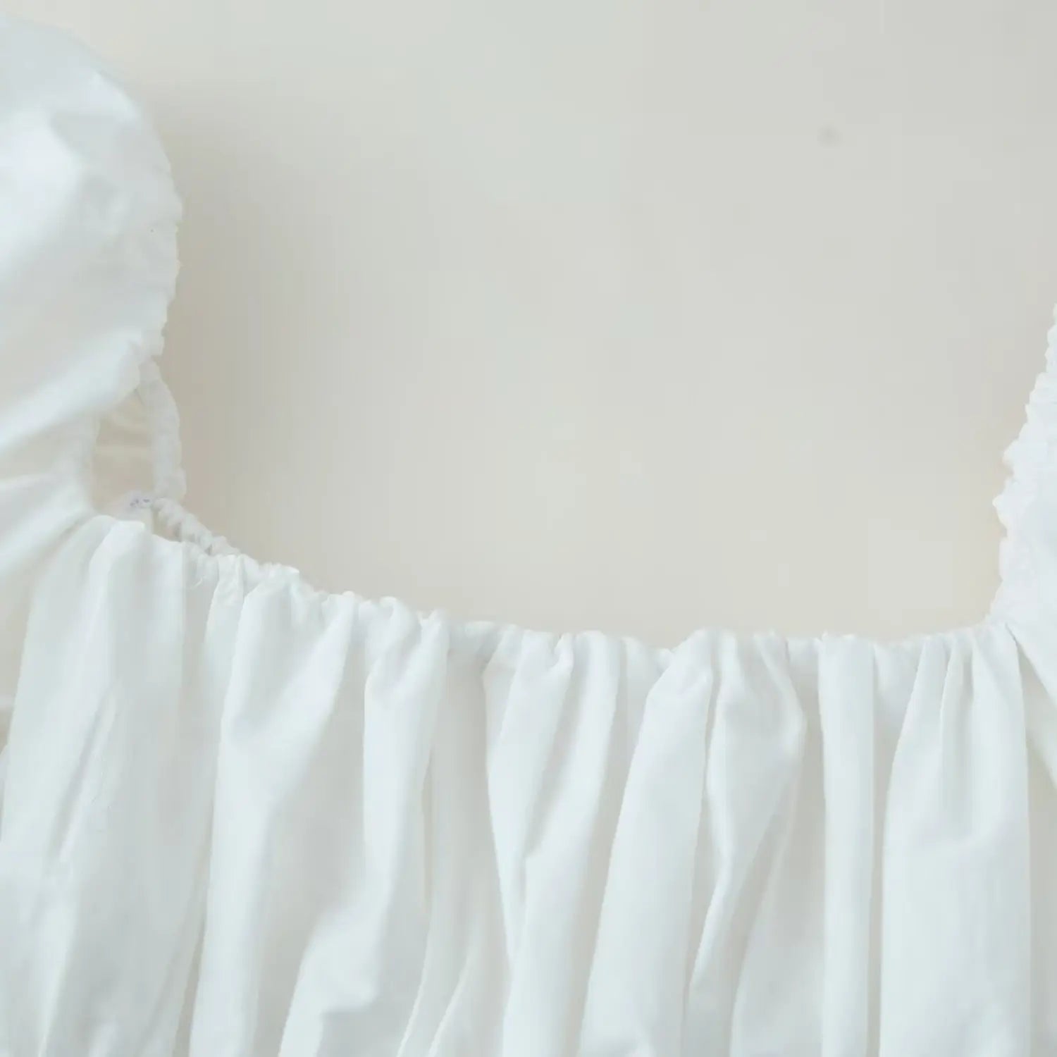 Detail of wide square neckline and full horizontal elastic gathering across bust woven upper section