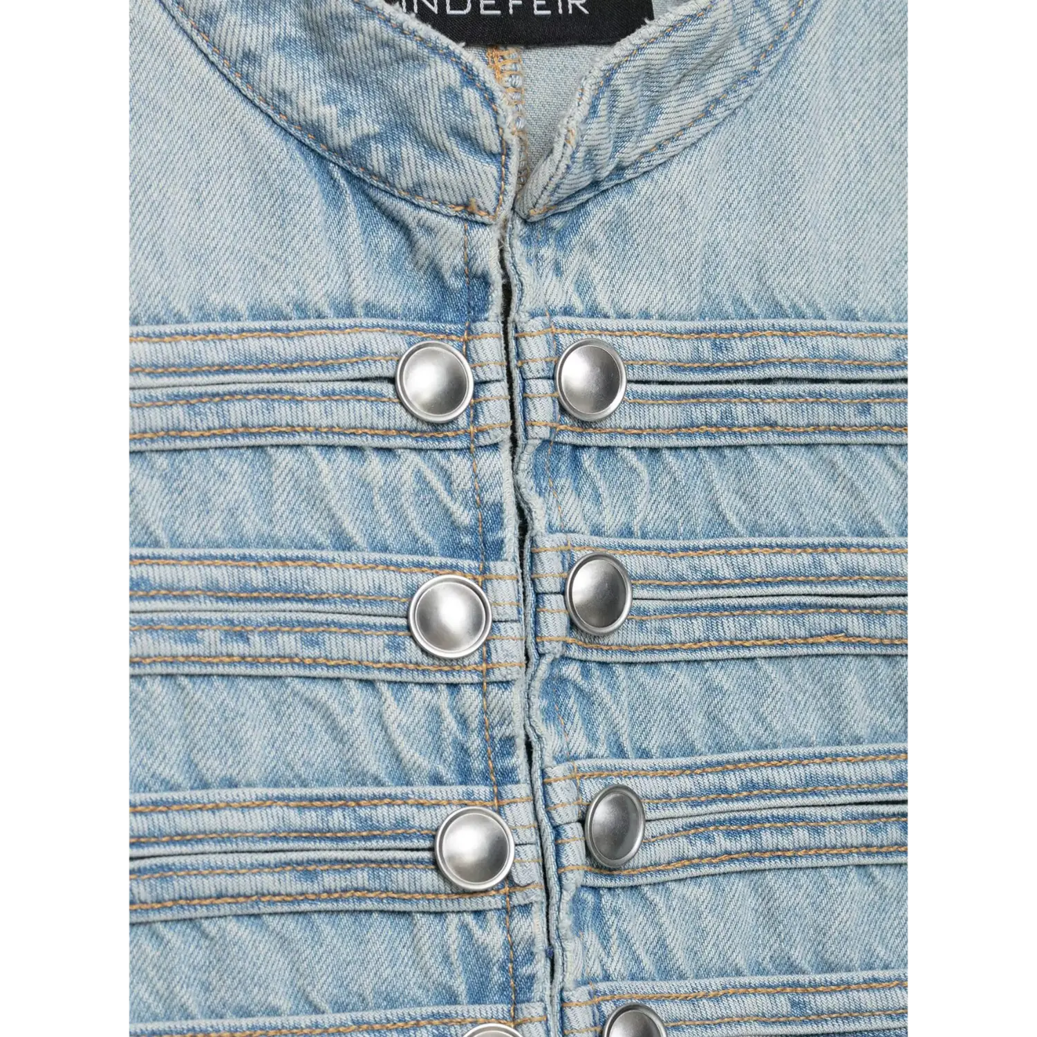 Macro shot stand collar and silver button strap detailing on light blue denim vest