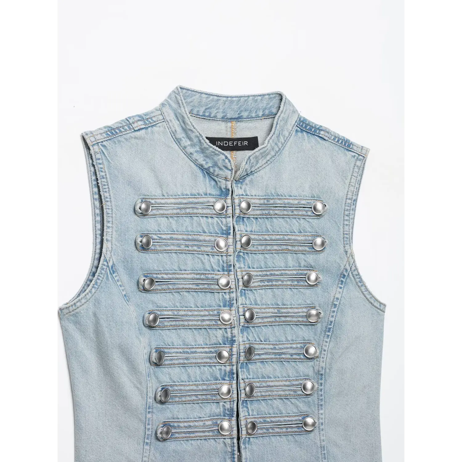 Close-up front of stand collar denim vest, decorative silver buttons and layered strap detailing