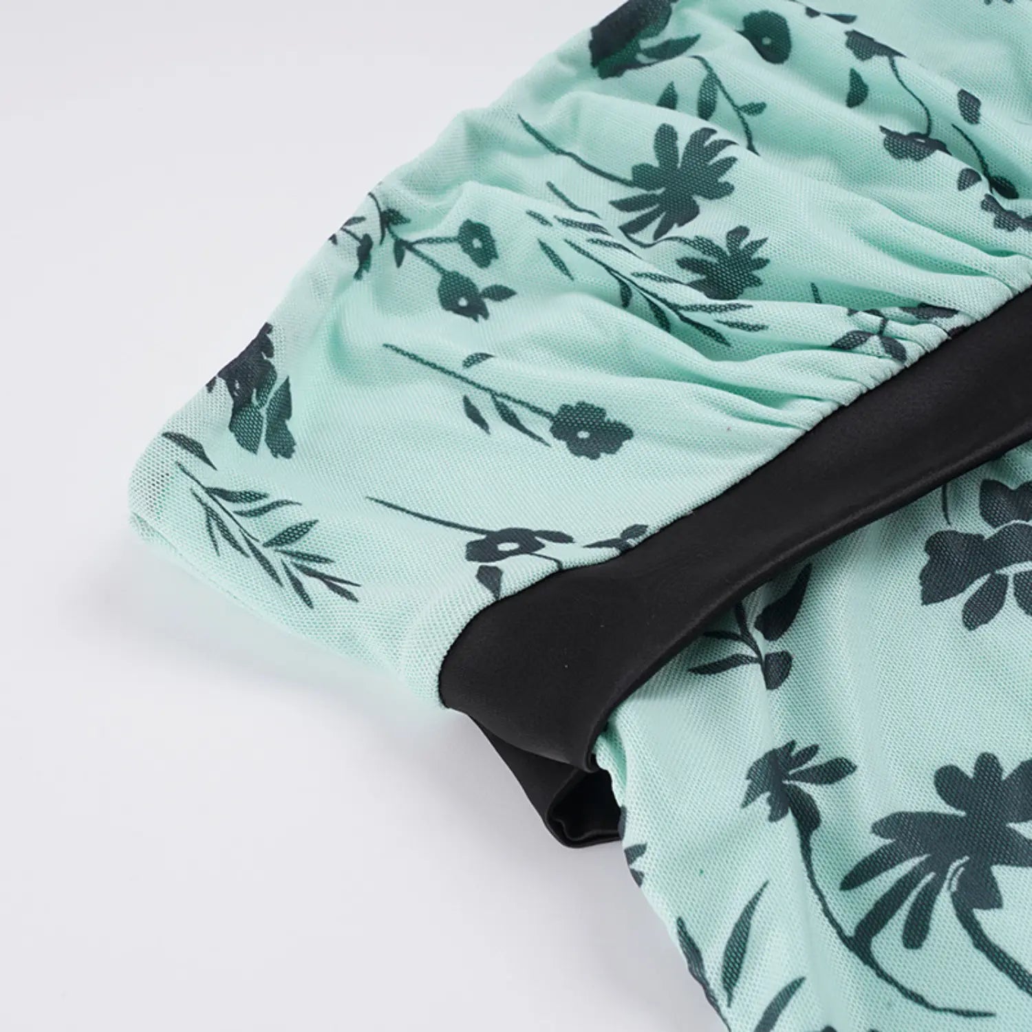 Partial side shot of bandeau tube top elastic gathered waist seam, black satin waist trim, sheer mint mesh with dark green floral print, curved body shaping silhouette