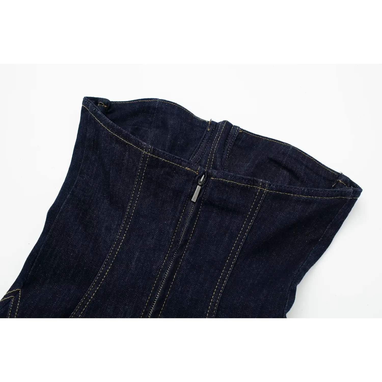 Close‑up of strapless dress back opening with exposed metal zipper, dark indigo denim with contrast stitching