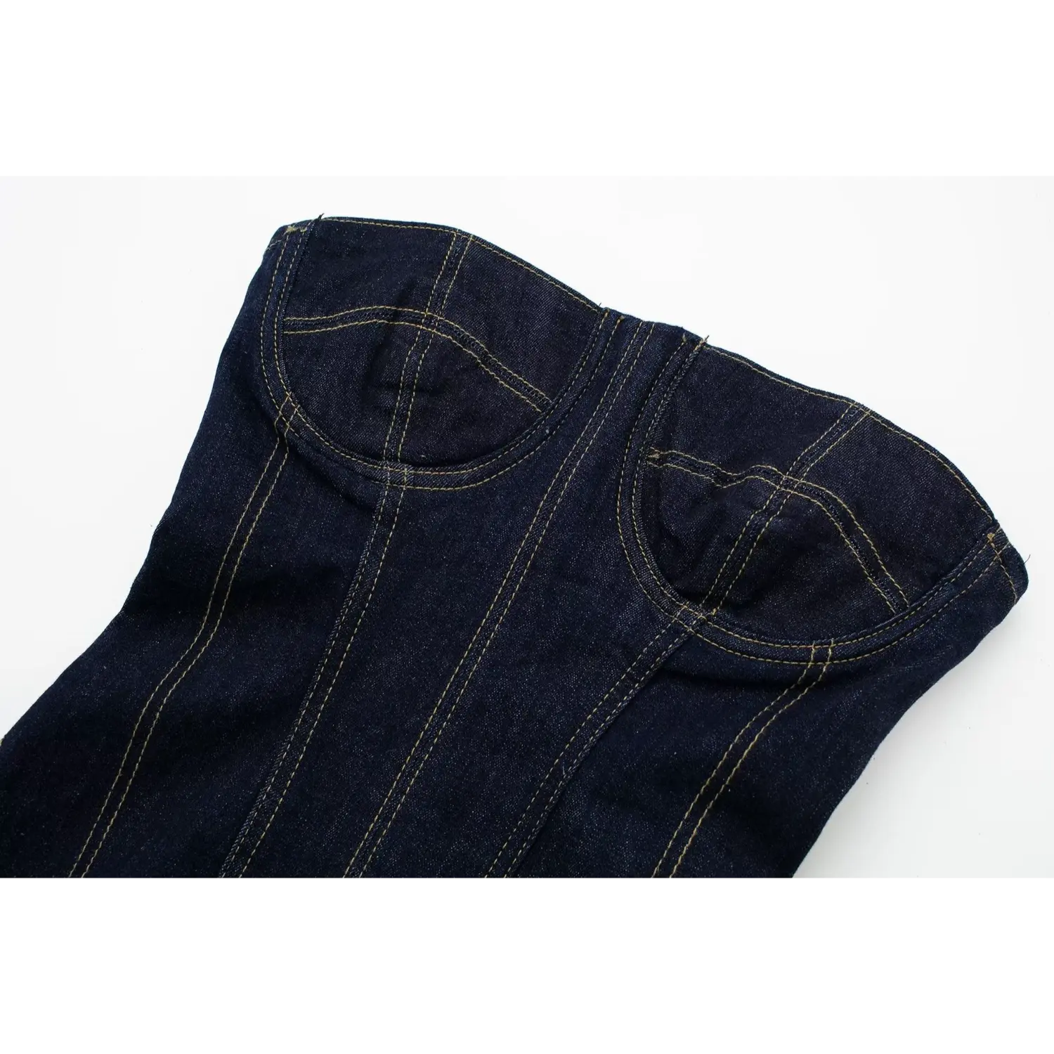 Close‑up of strapless bust corset seaming with contrast yellow stitching on dark raw denim fabric