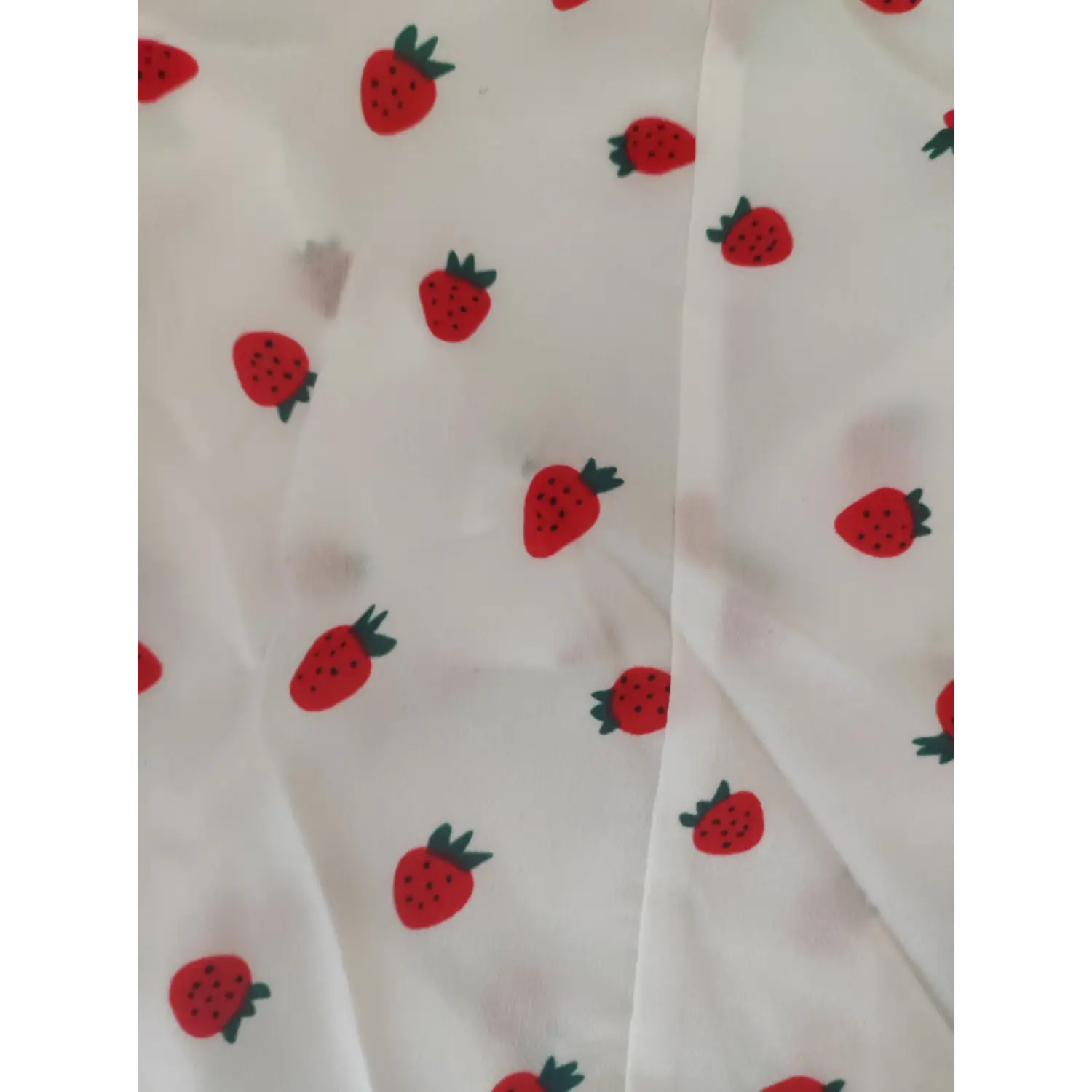 Close-up texture of red strawberry print lightweight white blouse fabric