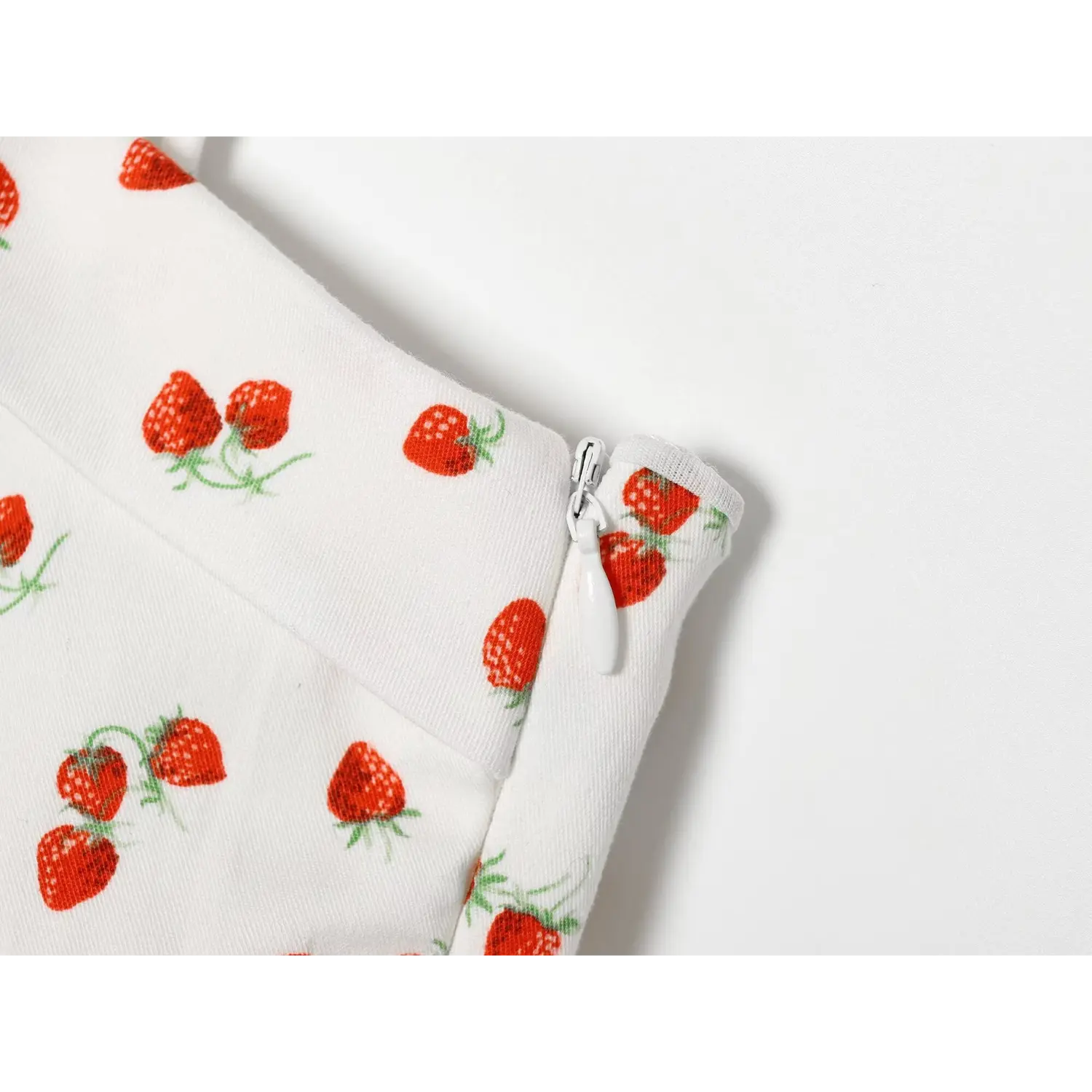 Close‑up shot of side invisible zipper detail on white strawberry print camisole top