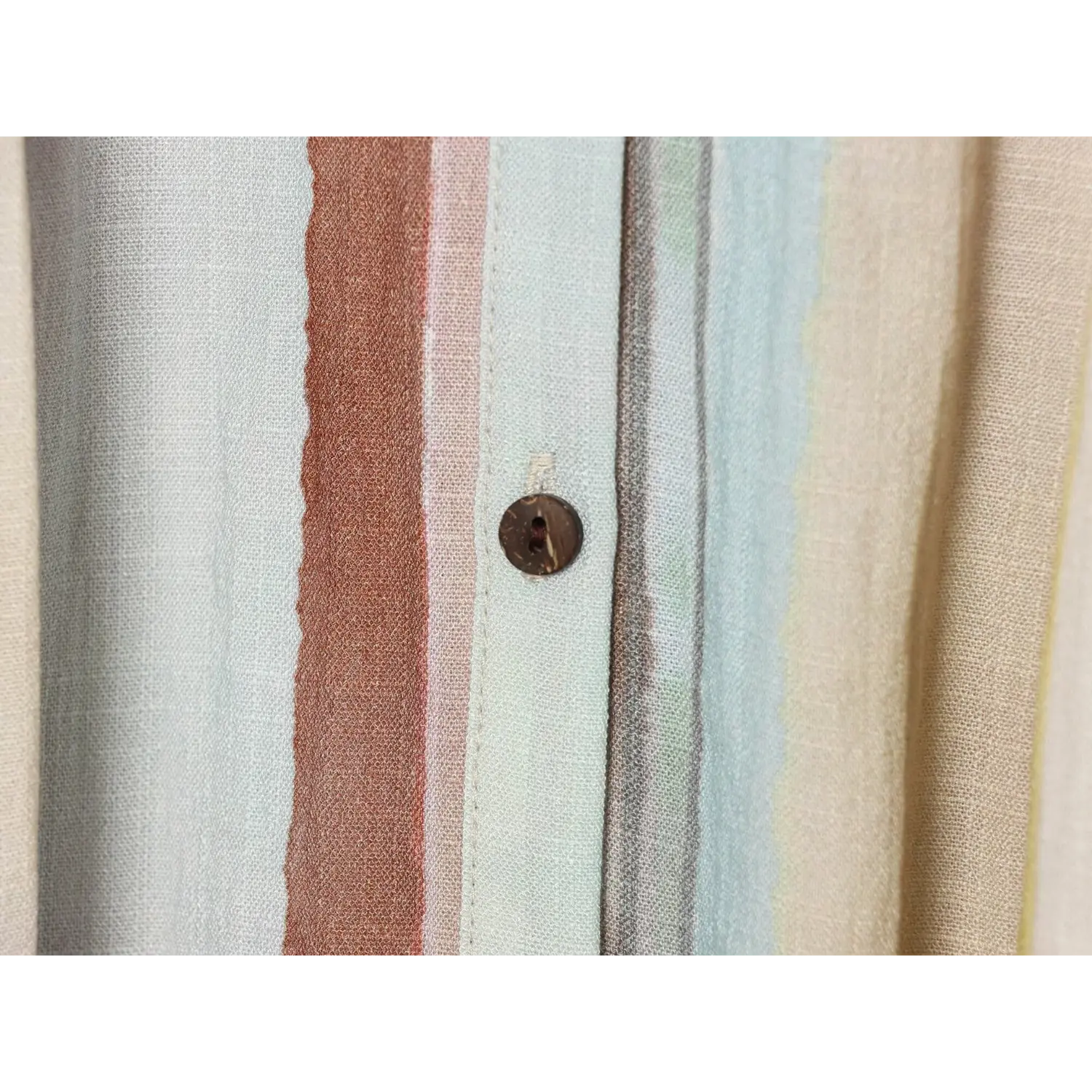 Macro close‑up of natural coconut shell button on striped woven midi dress placket