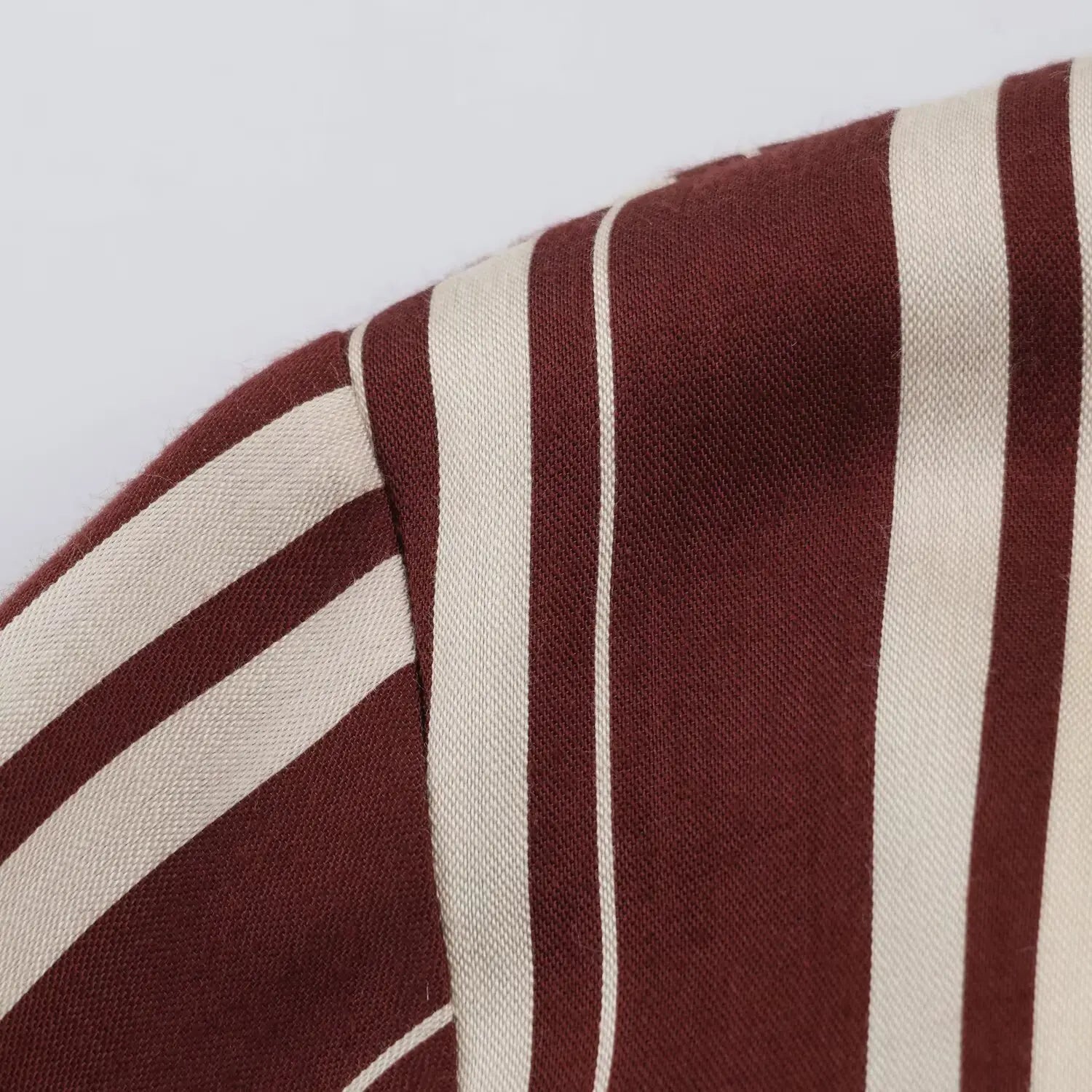 Close‑up texture of burgundy and cream vertical stripe woven fabric at shoulder seam