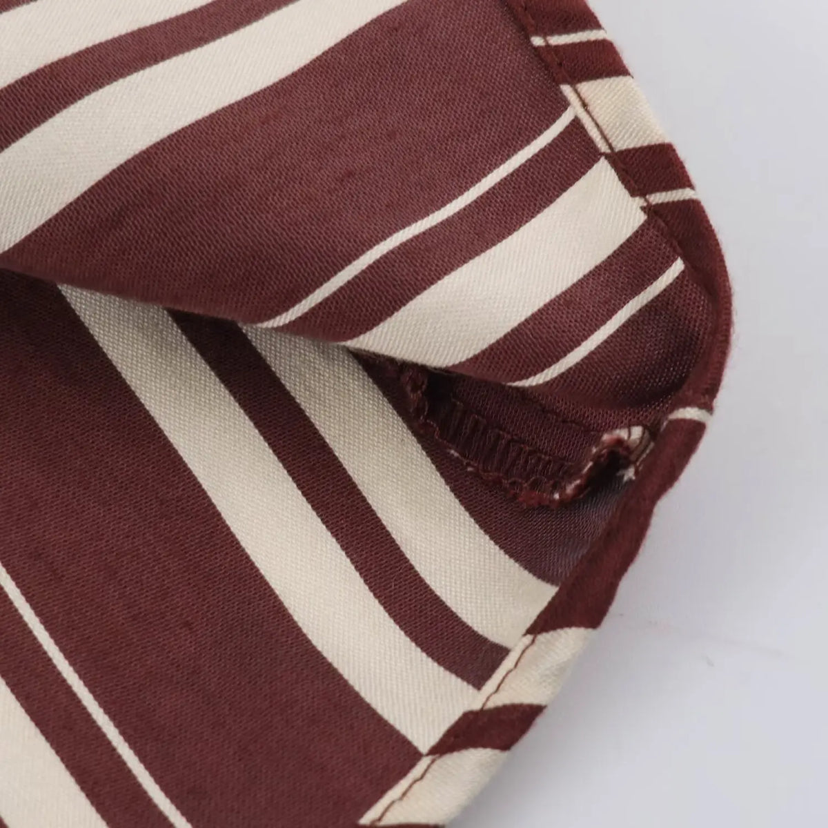 Macro shot of inner stitching and fabric hem detail on striped long shirt dress
